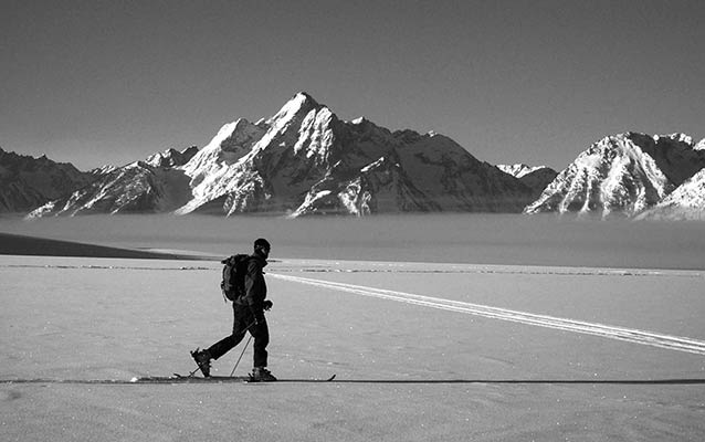 A skier, dressed for winter, skis with the Teton Range in the background. A skier, dressed for winter, skis with the Teton Range in the background.