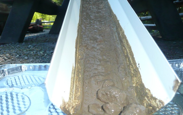 A mud slurry slides down a ramp into a tray. A mud slurry slides down a ramp into a tray.