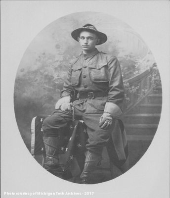 Black and white studio posed portrait of a man in a soldier's uniform holding a revolver in his hand