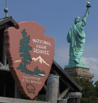 A view from the dock of the Statue of Liberty with the National Park Service arrowhead in the foreground,