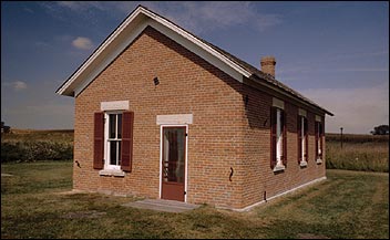 One room, red brick, red door school house in a flat, prairie setting