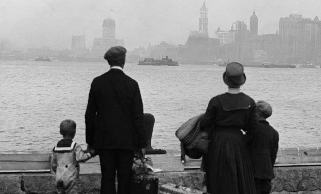 Newly arrived immigrants looking at New York City from Ellis Island.  Historic photo.