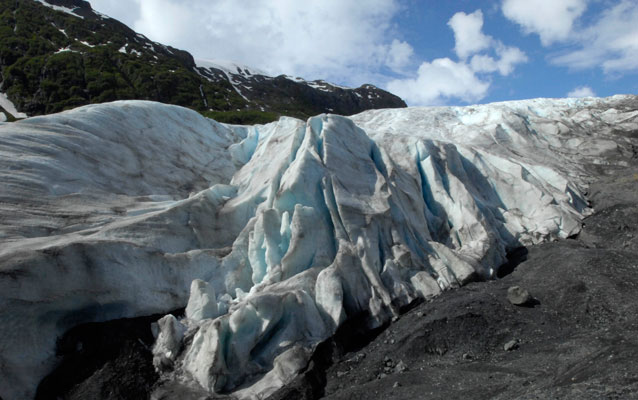 A glacier, gray rock and blue sky.
