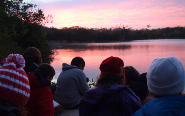 Students at sunrise by a lake