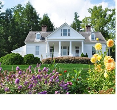 Historic home on a grassy hill with yellow and purple flowers 
