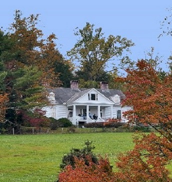 Color photo of Carl Sandburg's Historic Home and lawn with fall leaves in the foreground. 