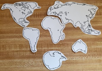 Paper cutouts of the seven continents arranged on a table as they are on a modern map.