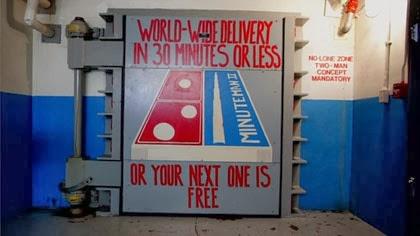 Large square gray door with a dominos pizza logo painted on it Large square gray door with a dominos pizza logo painted on it