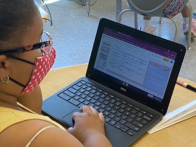 A student looks at a computer screen in a classroom. A student looks at a computer screen in a classroom.