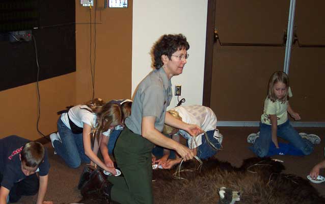 A female ranger on her knees surrounded by children.