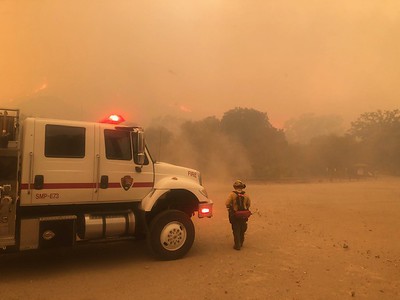 A firetruck and firefighter stand in the middle of a smokey environment at Paramount Ranch during the 2018 Woolsey Fire.