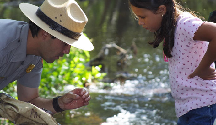 A ranger shows a student an invasive species found in a local stream. A ranger shows a student an invasive species found in a local stream.