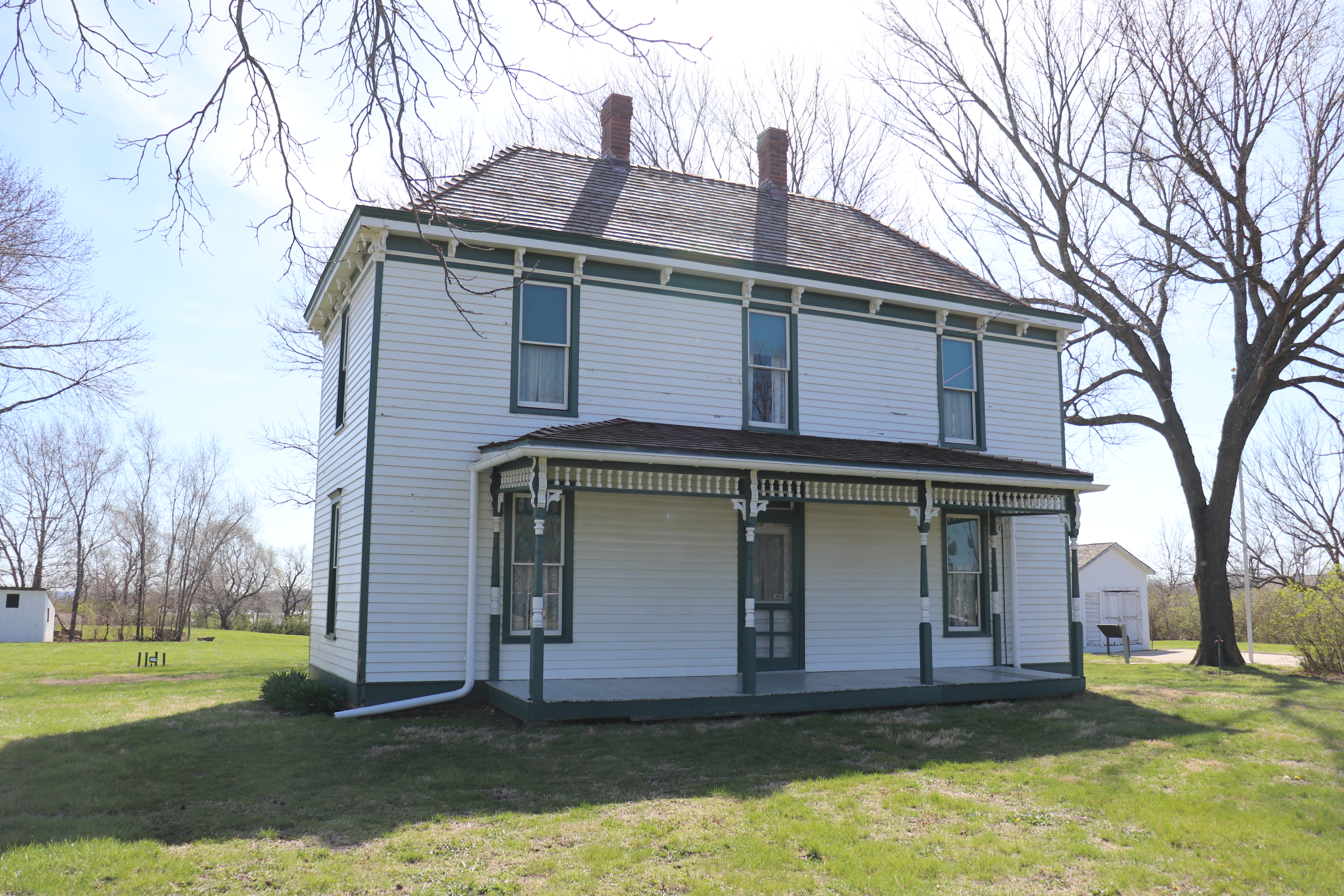 The two-story white Truman farm home with a front porch and green trim.