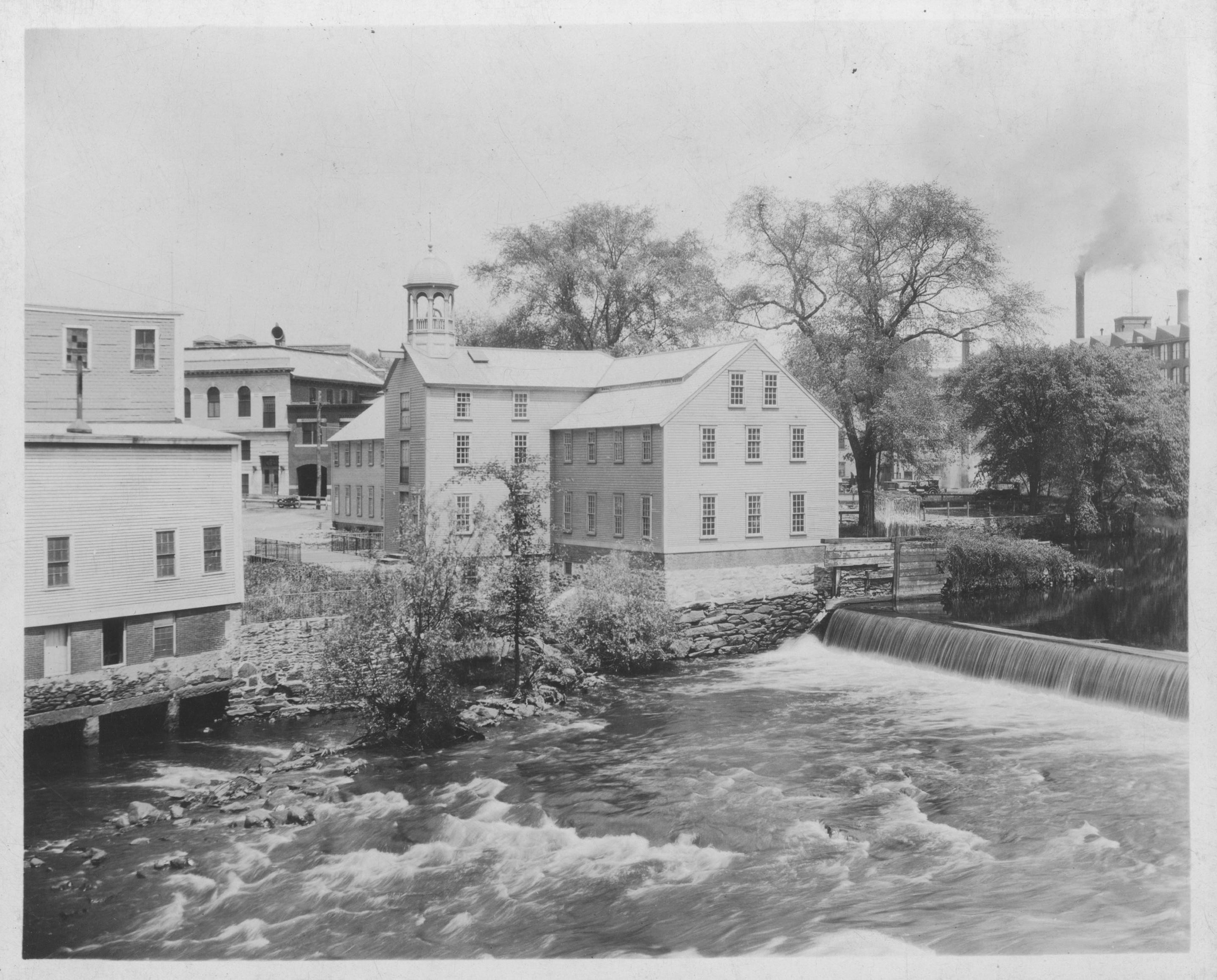 Old Slater Mill with belltower on the banks of the Blackstone River with Slater Dam
