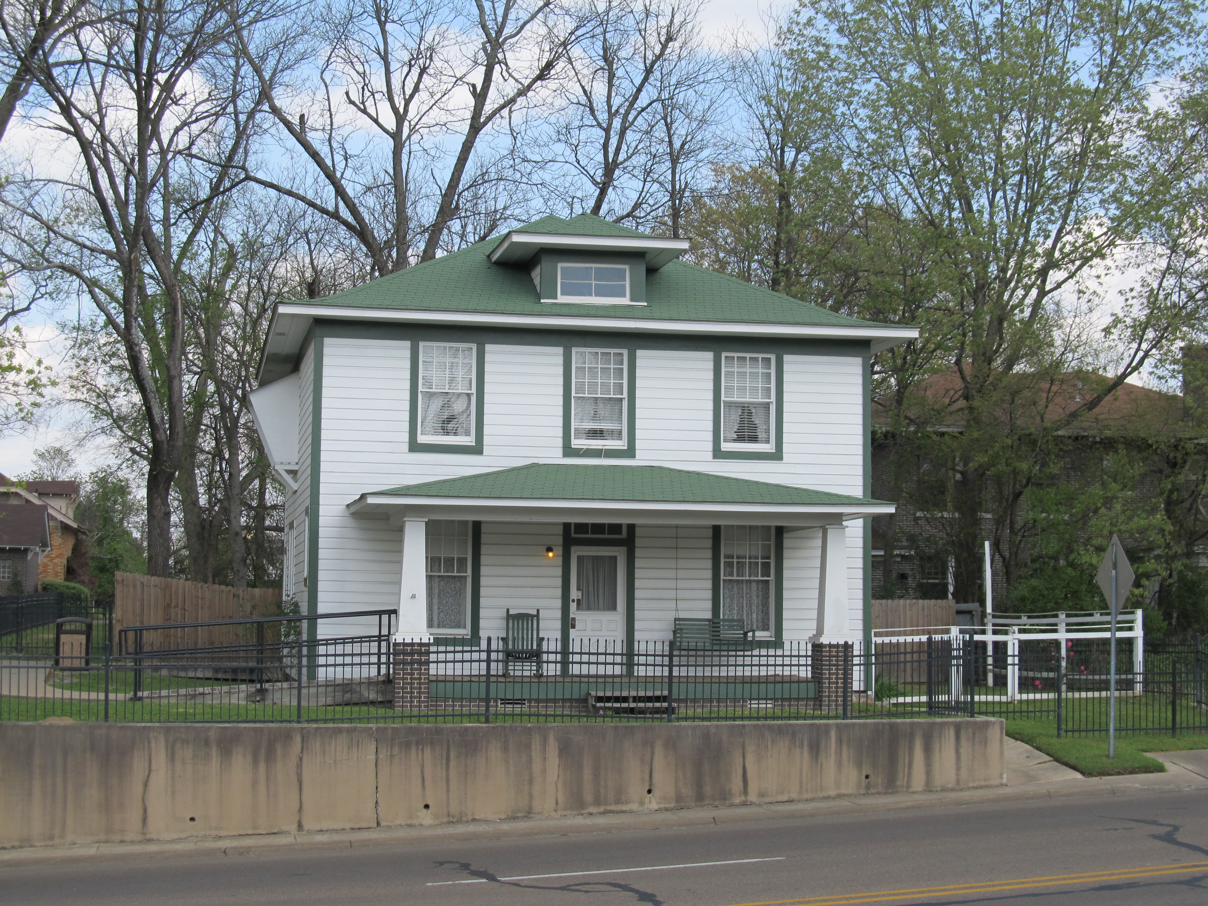 A two story white house with green trim in the American four square design