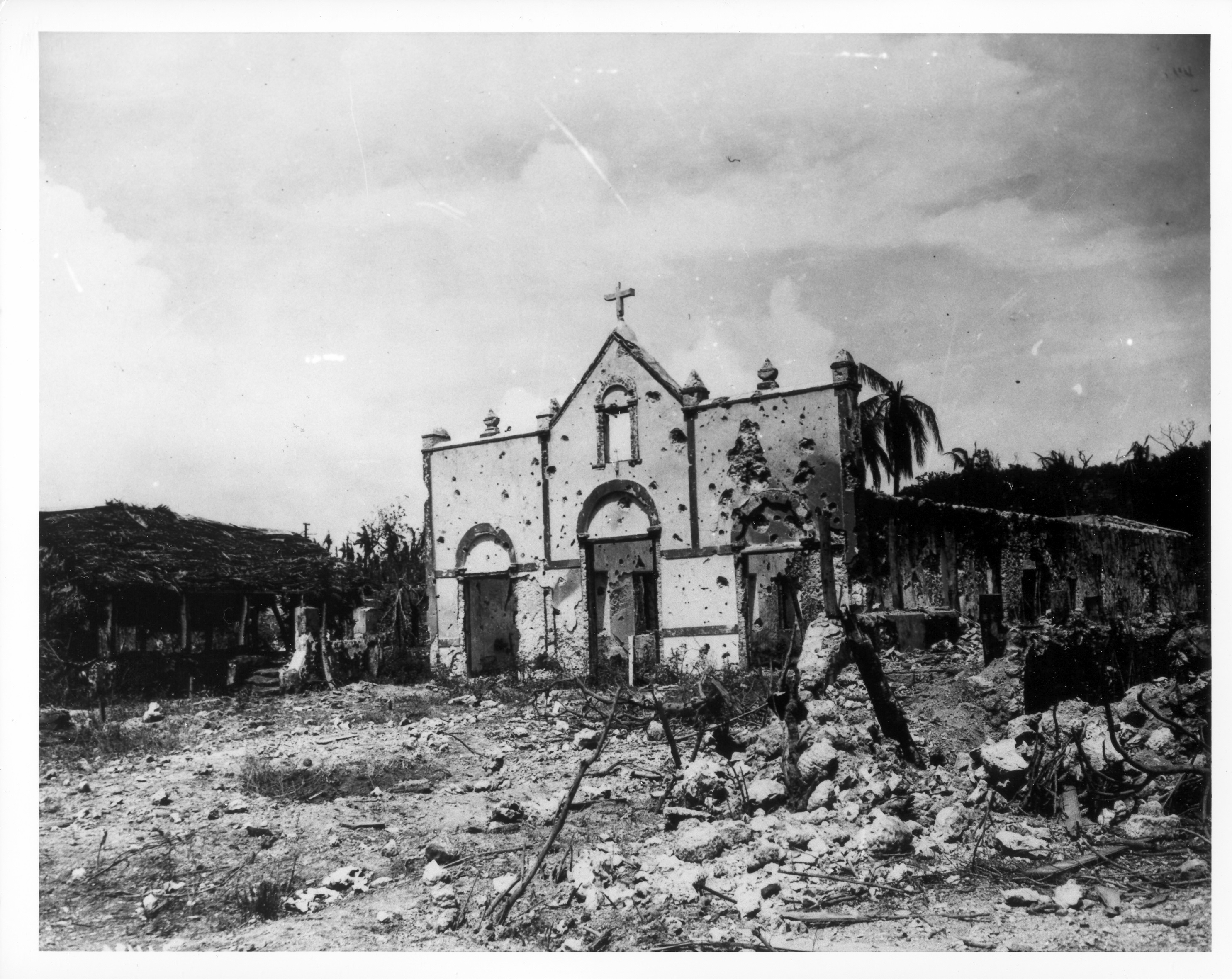 A black and white photo of an embattled church&mdash;pocked with bullet holes, and surrounded by debris.