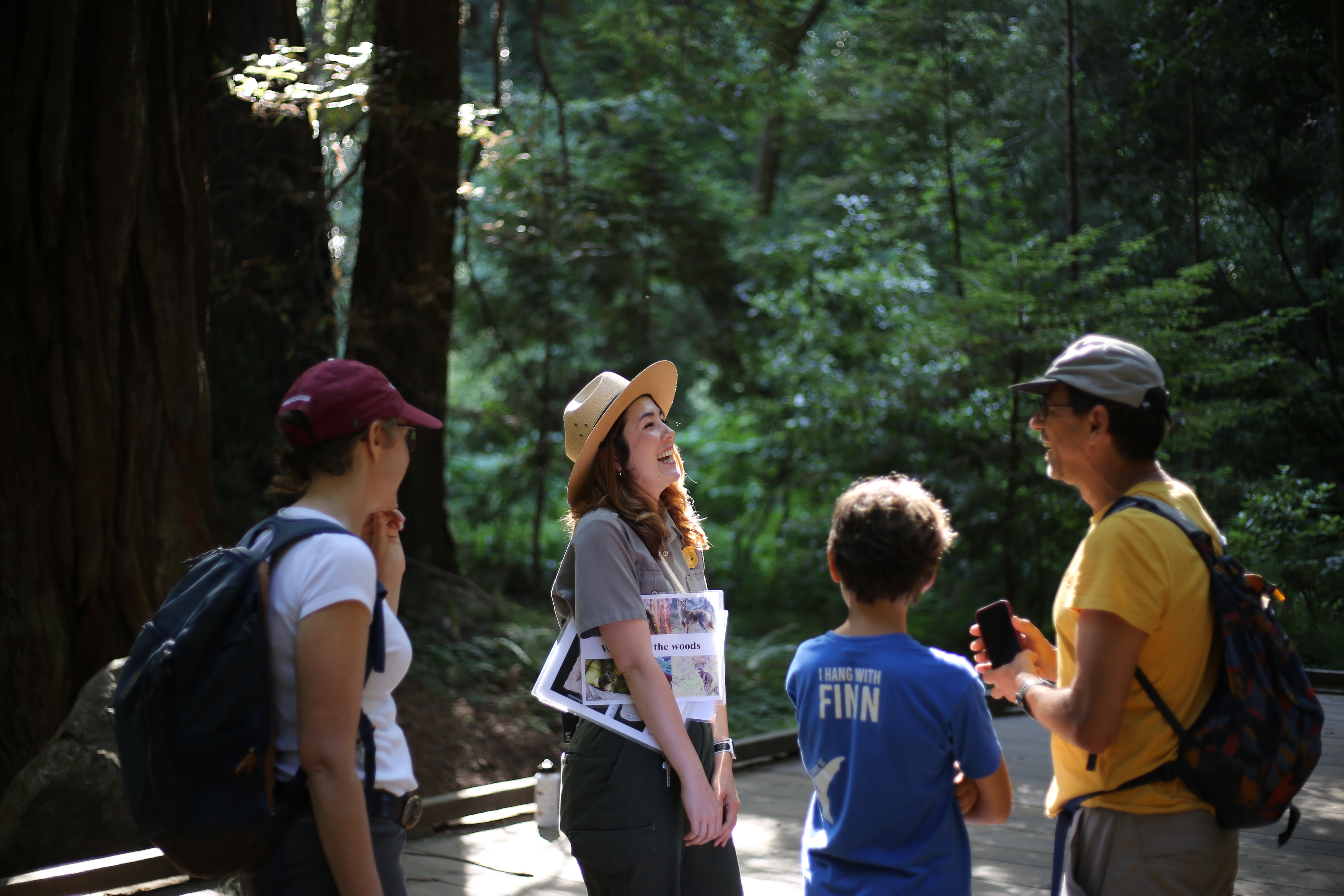 A ranger laughs while talking with visitors in the forest