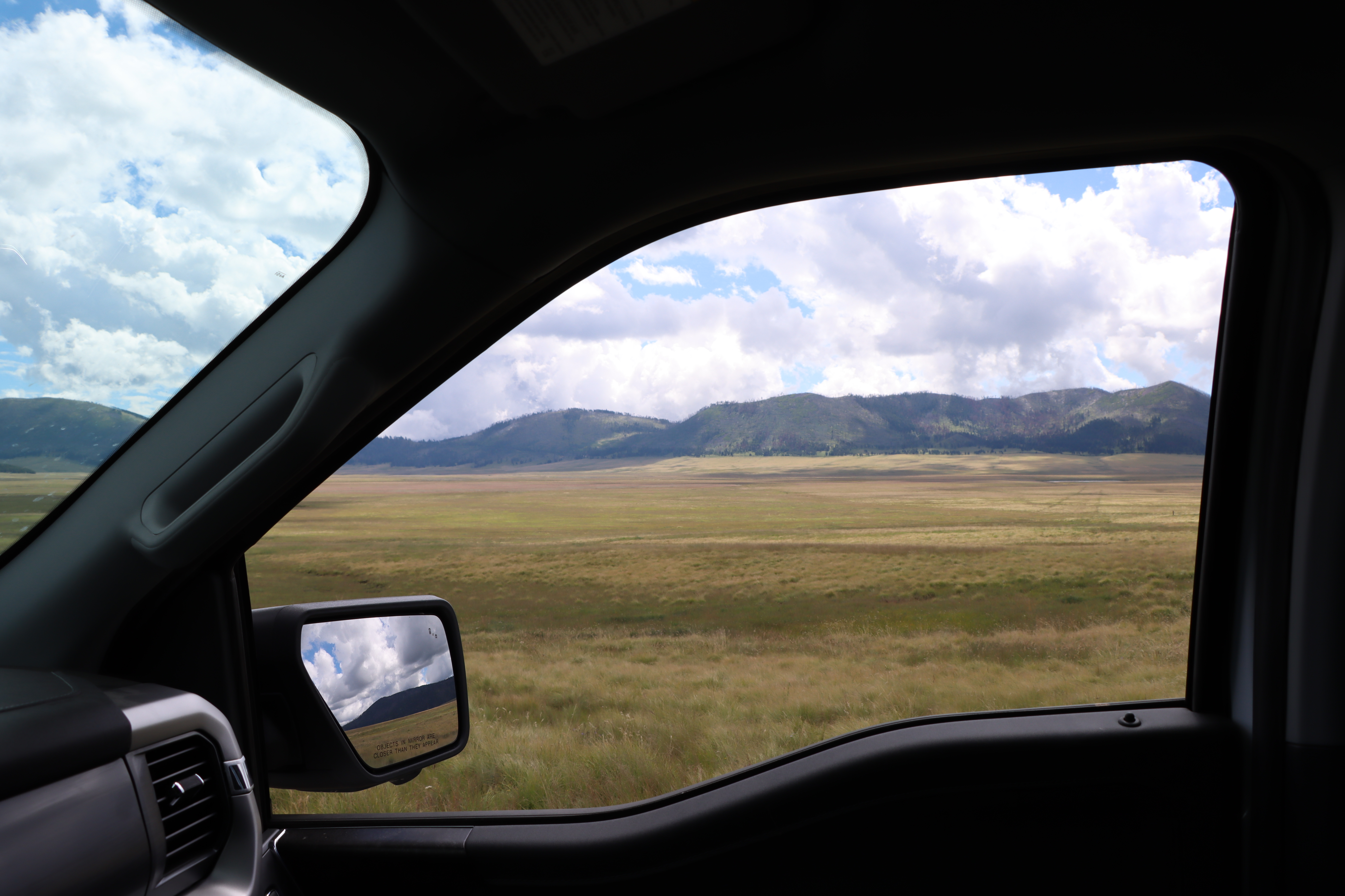 Looking out a truck window into a large grassland.