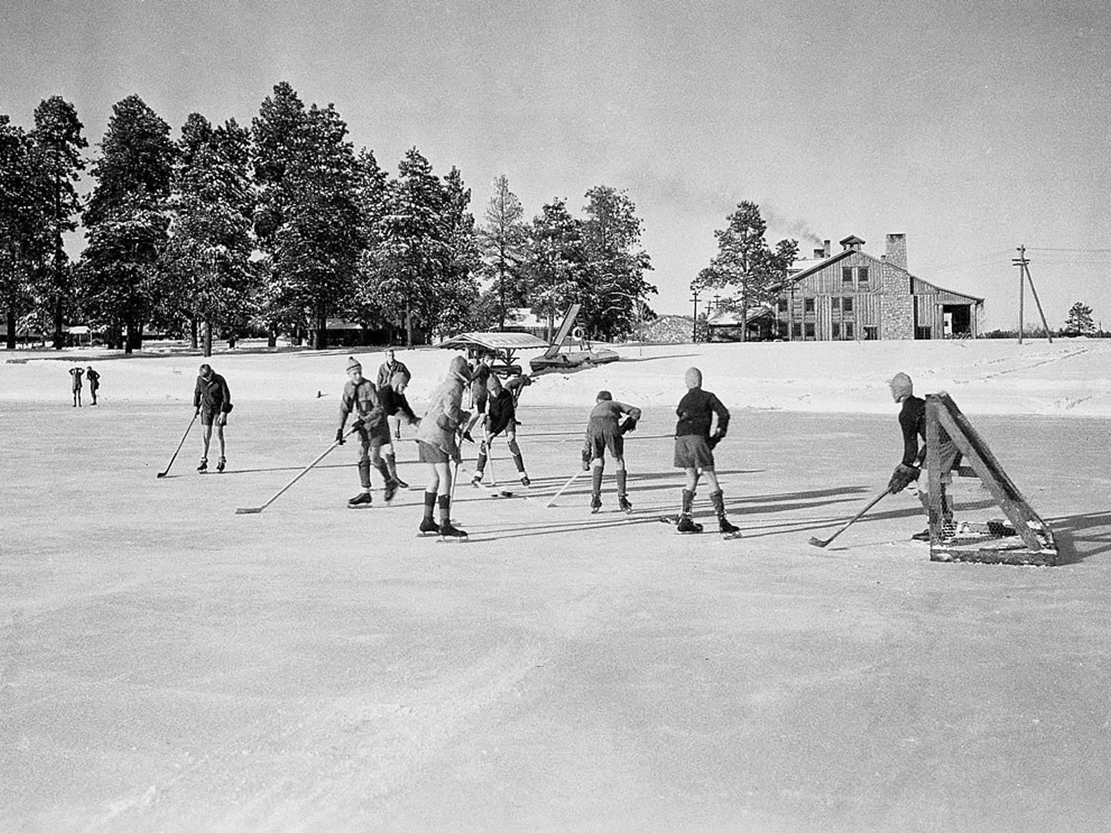 Youths play ice hockey on a frozen pond.
