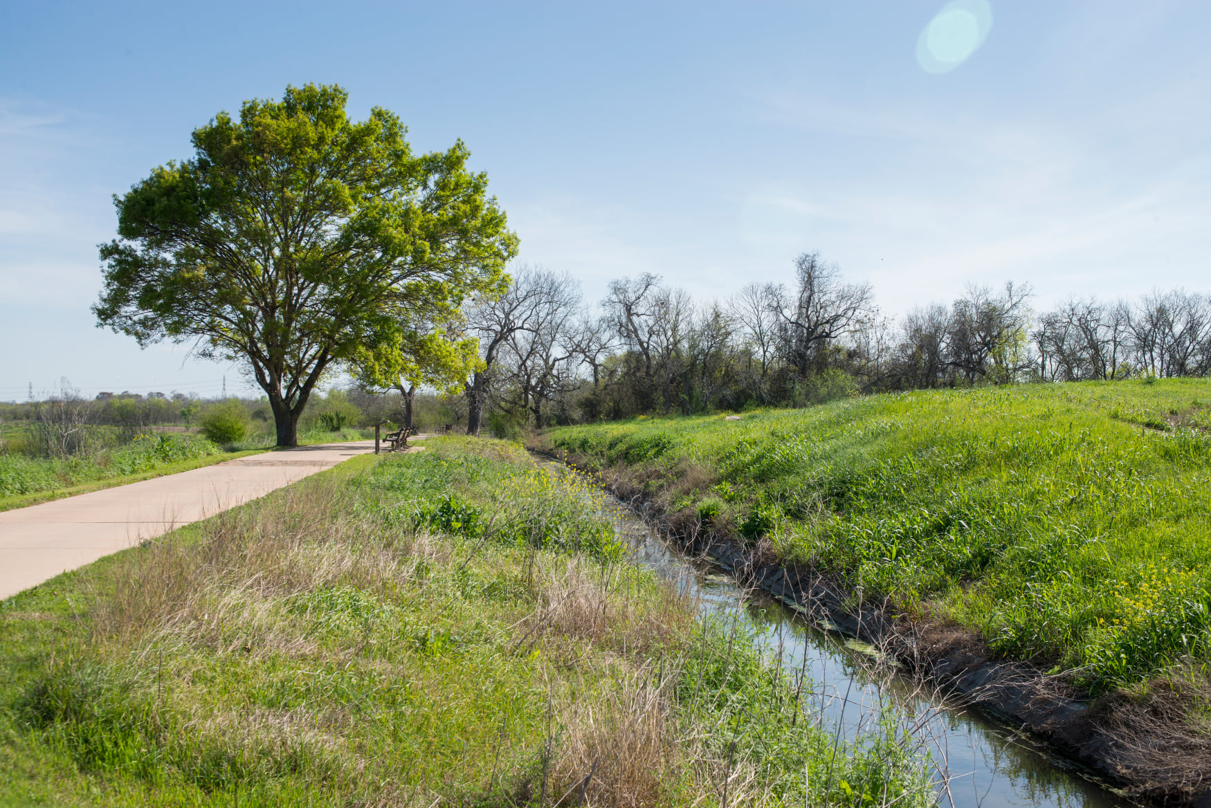 Paved path travels along the historic irrigation ditch filled with water.