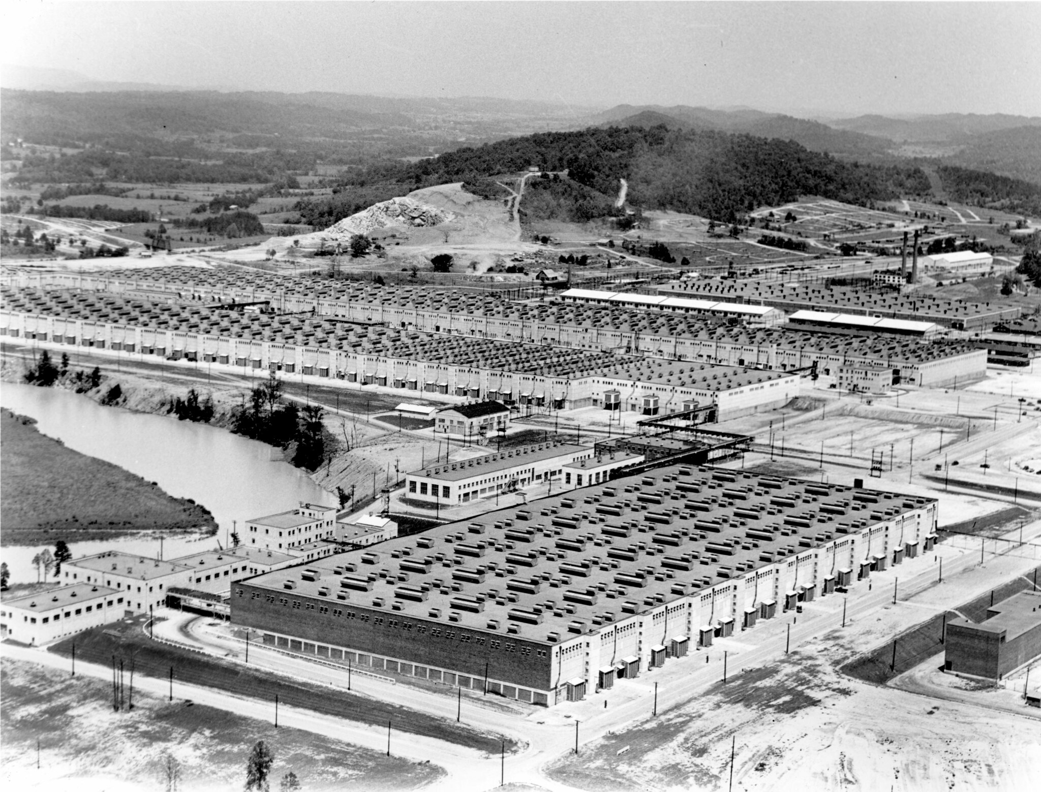Aerial photo of large industrial complex in wooded valley.