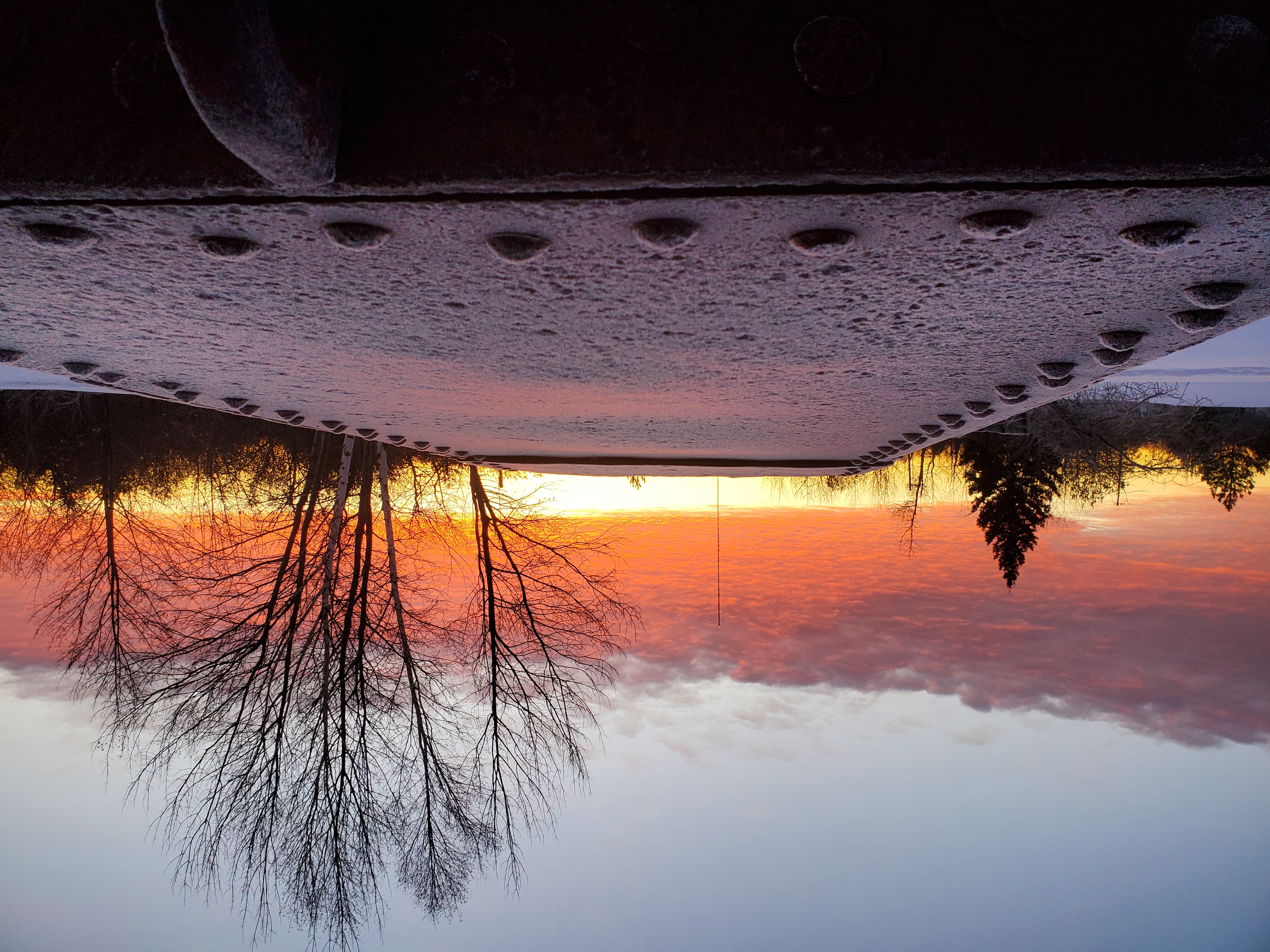 A rusty steel rectangular skip leads to a winter sunrise of red, orange and grey skies.
