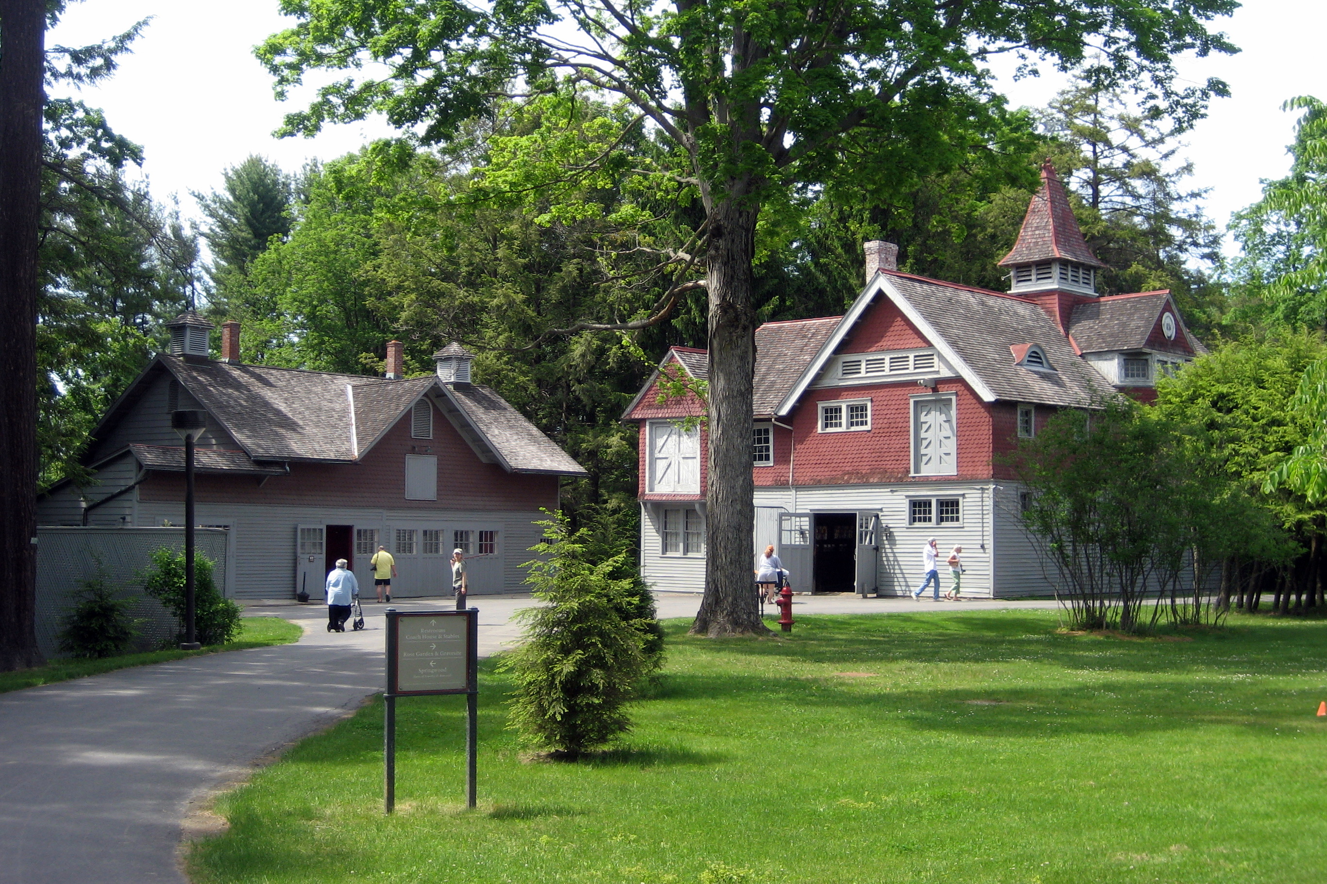 Two buildings clad in wood clapboard and shingles with steep pitched roofs, surrounded by a lawn.