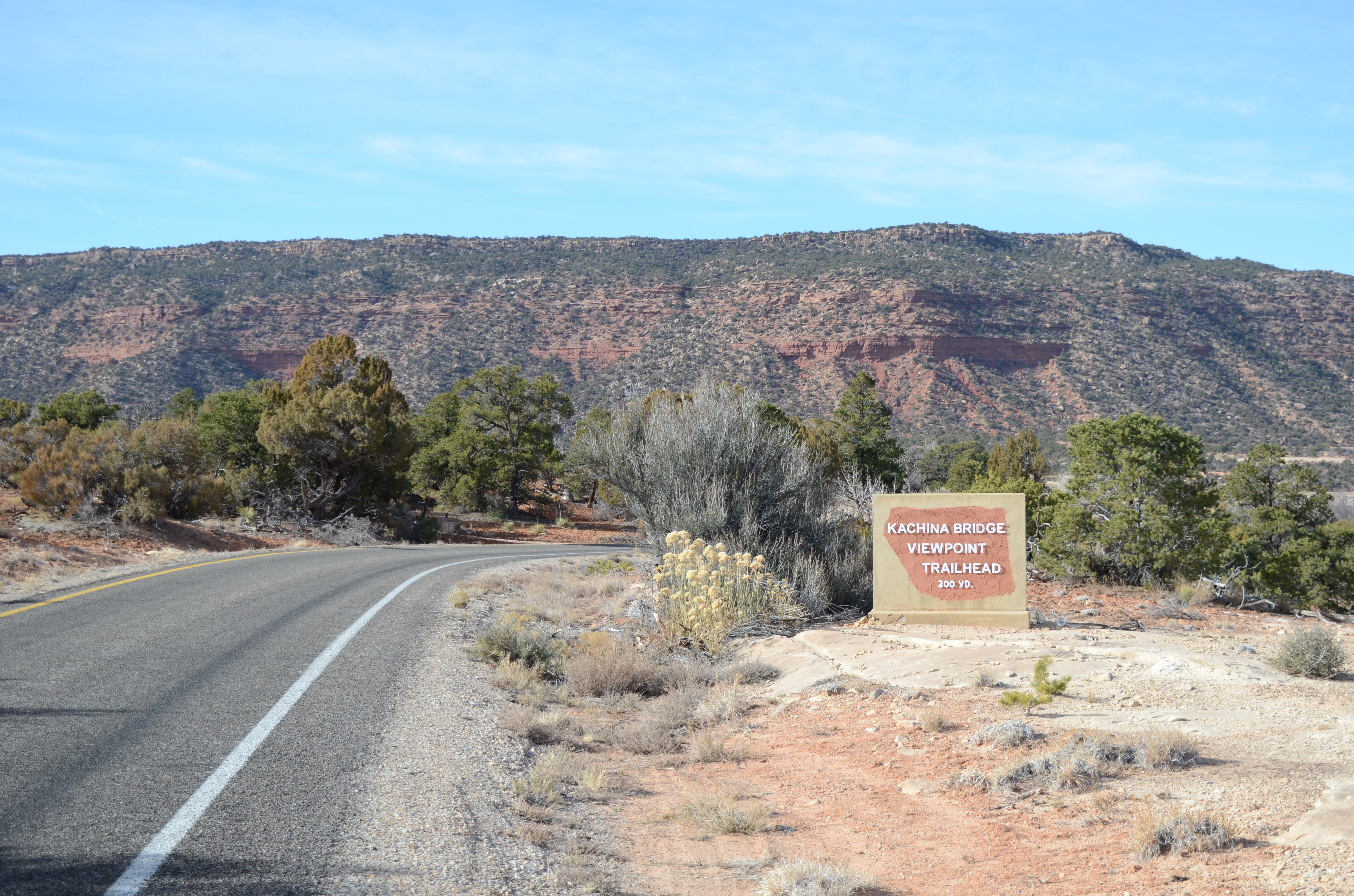 A stone sign marking the parking area for Kachina Bridge along a road in canyon country