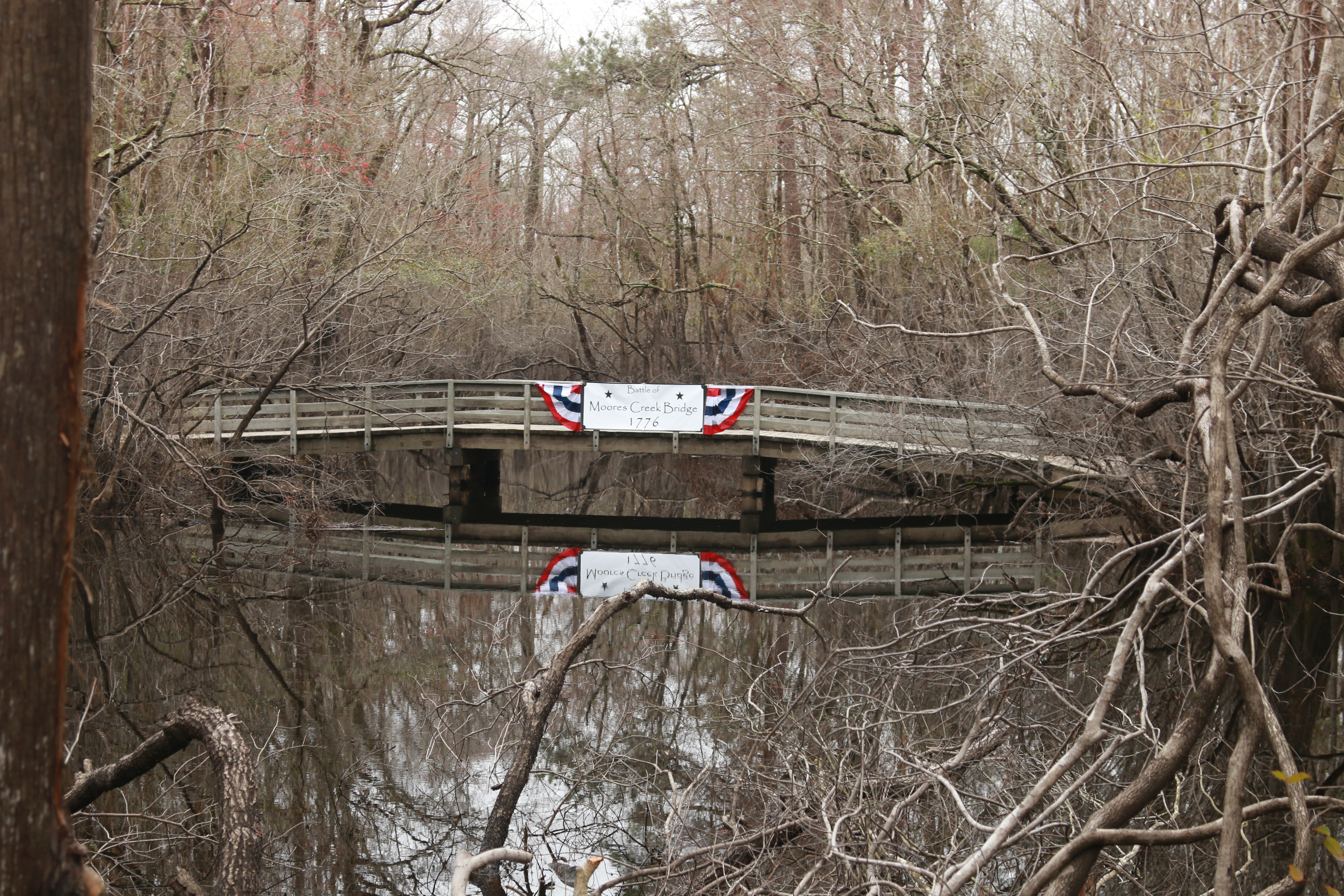 Bridge over a creek with a patriotic banner hanging on it.