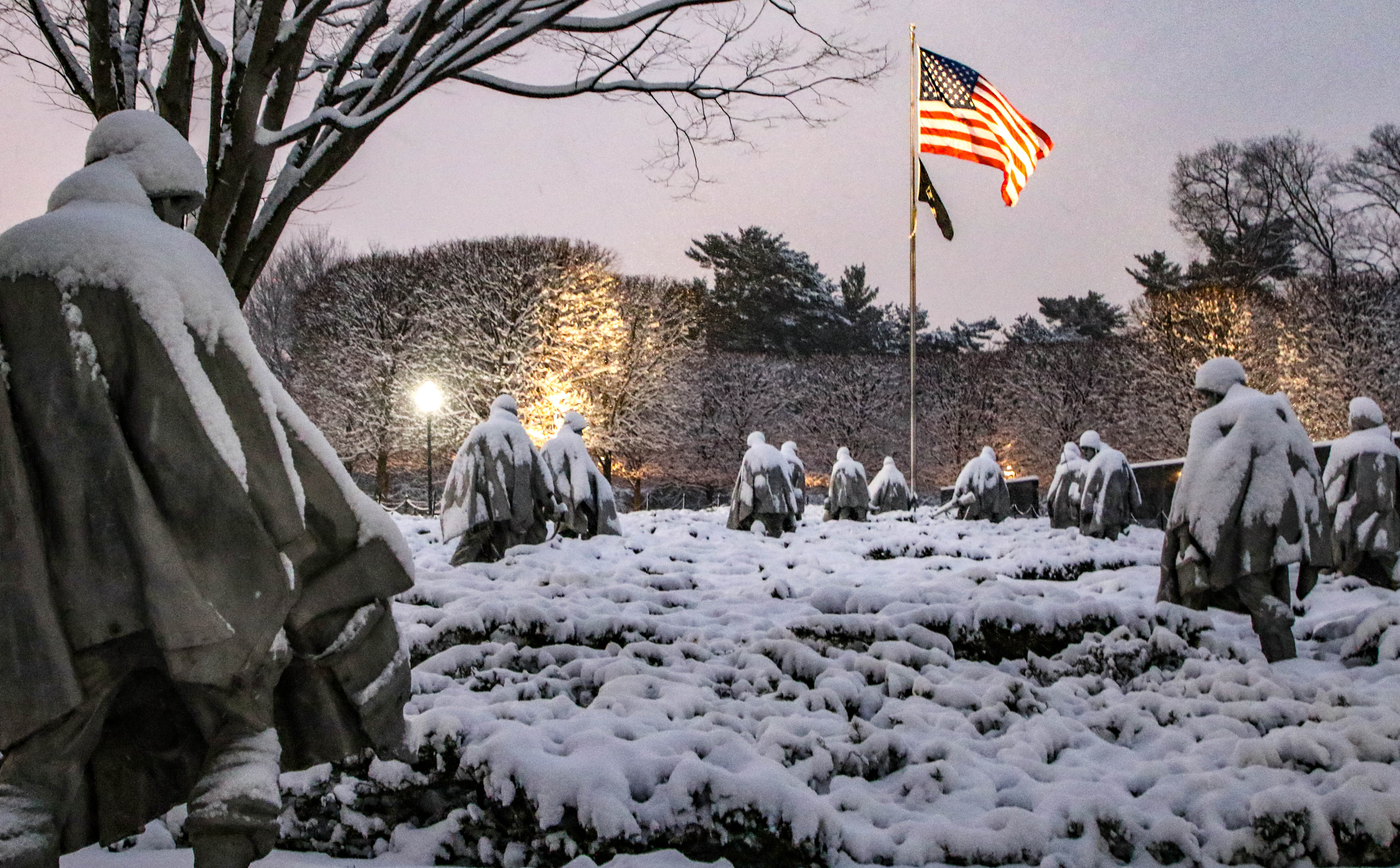 A field of snow covered soldiers walking towards an American Flag