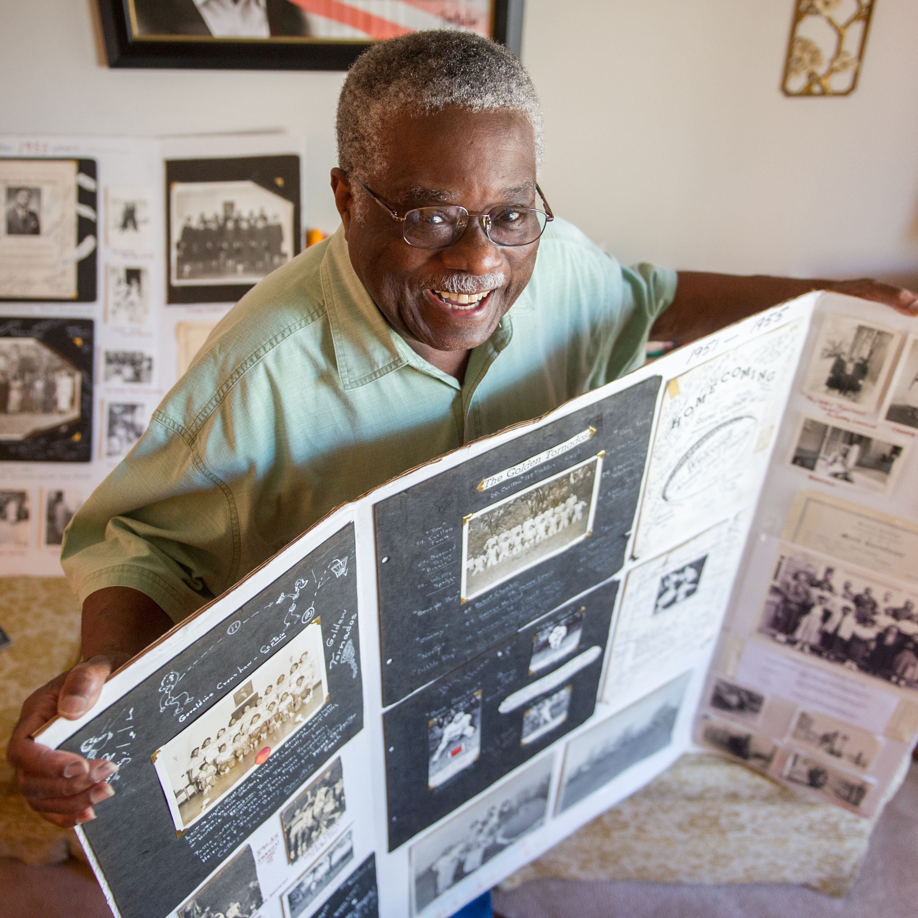 Smiling African American man looks directly into camera. He is holding a display board