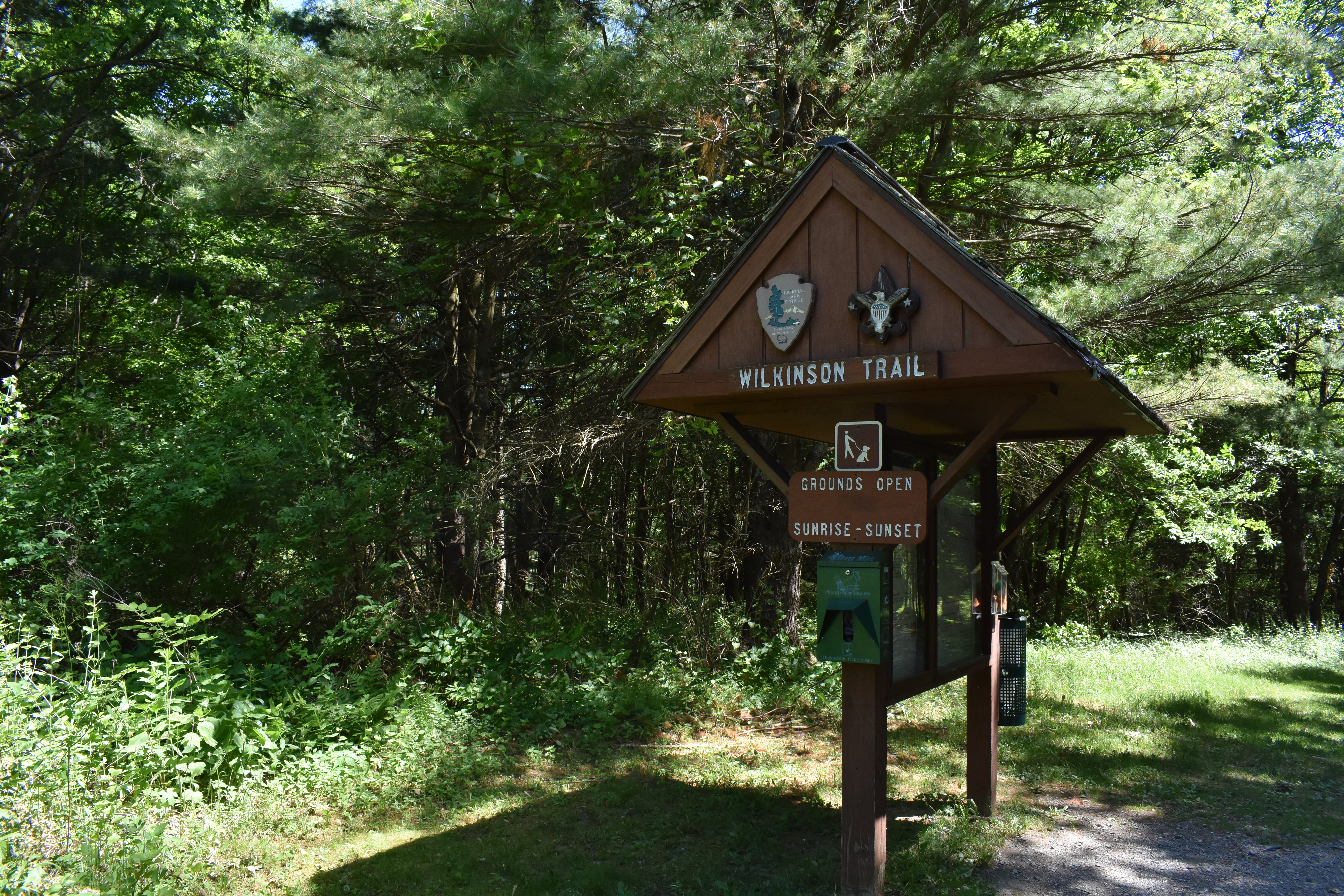 Brown, roof covered information kiosk at the start of a trail.