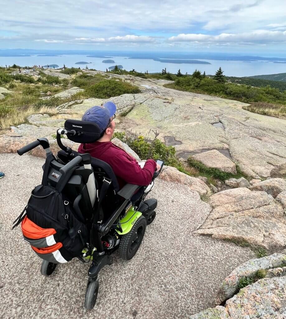 A man in a powered wheelchair views Cadillac Mountain's sweeping views of Frenchmen Bay