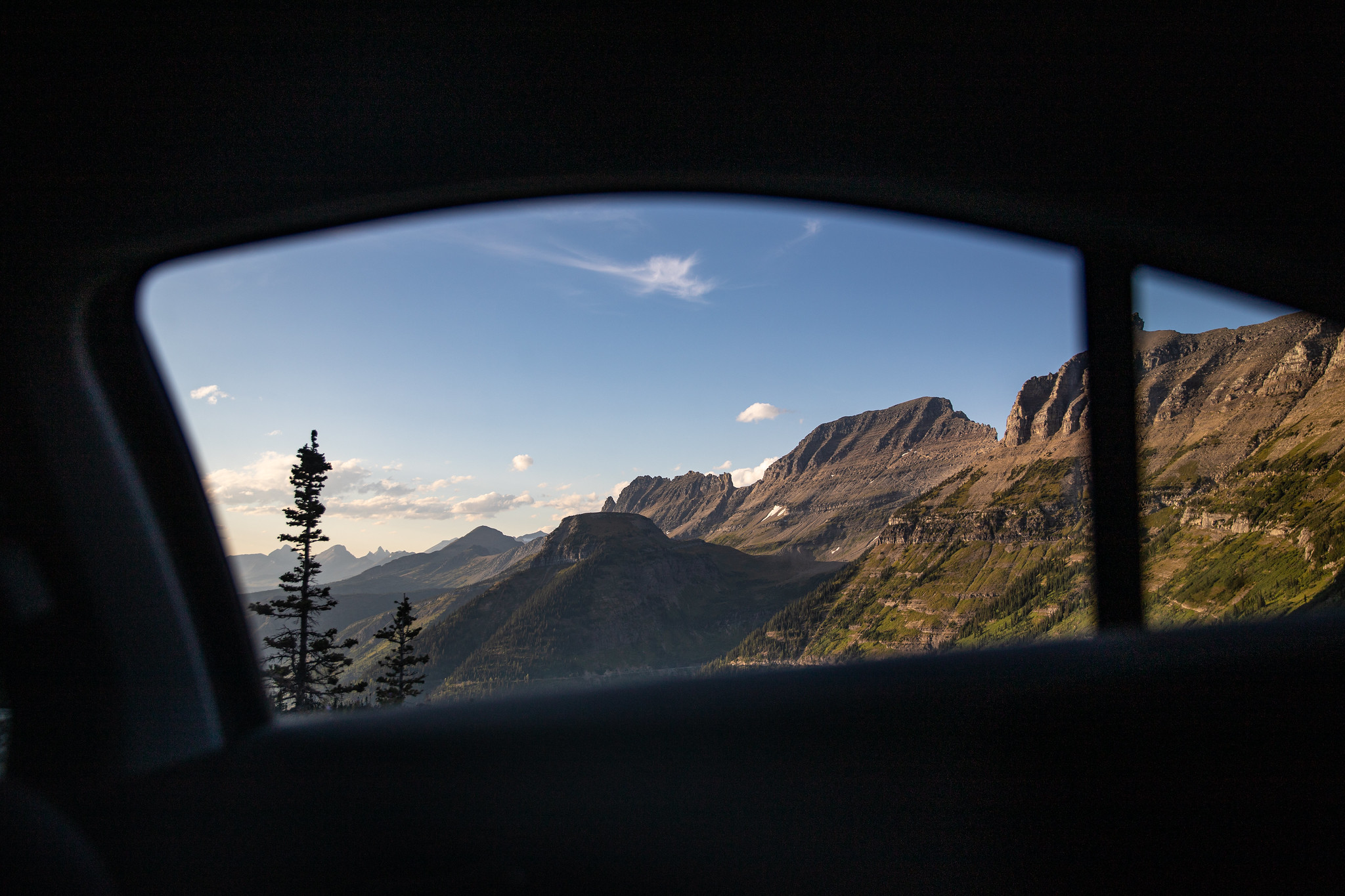 A nearly vertical mountain ridge is seen from a car window.
