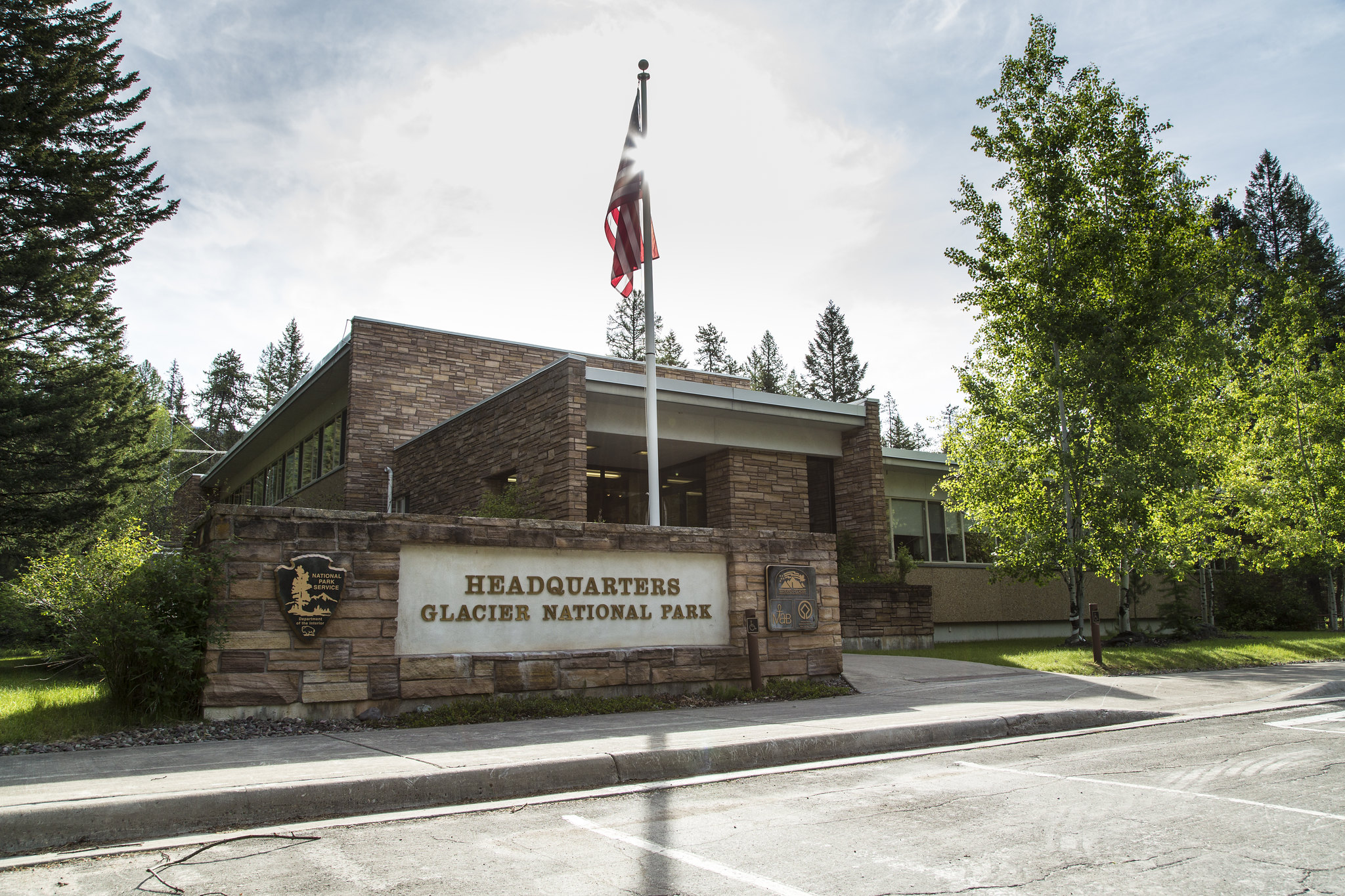 A low brick building with an American flag and a sign that says "Headquarters/Glacier National Park"