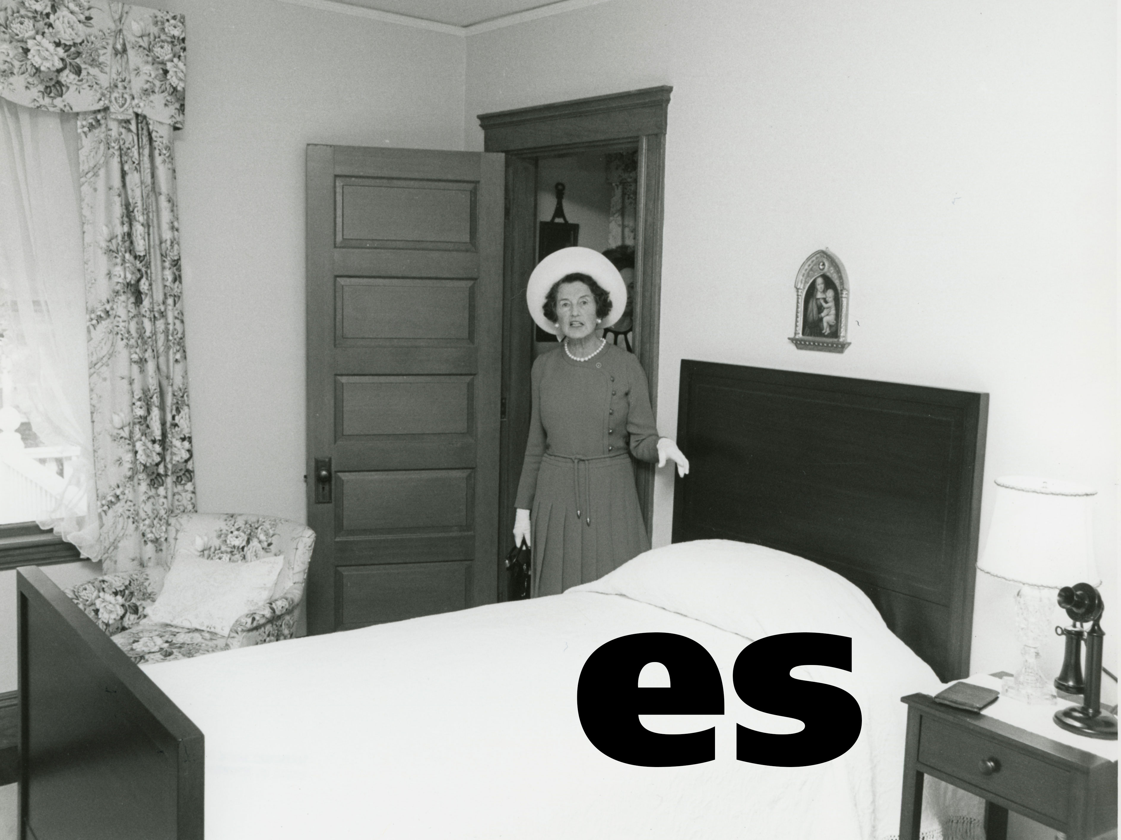 Woman in white hat standing next to twin bed