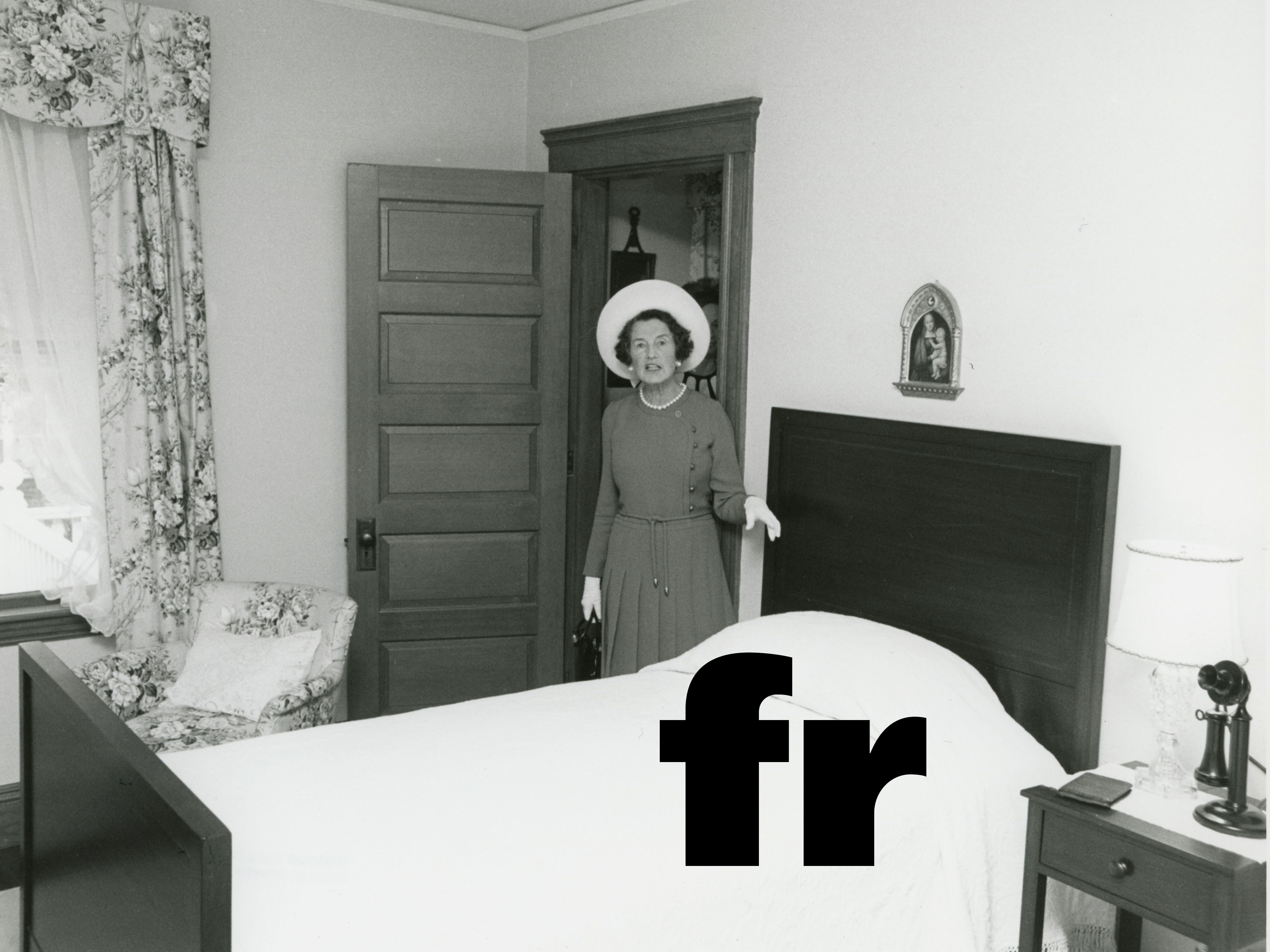 Woman in white hat standing next to twin bed