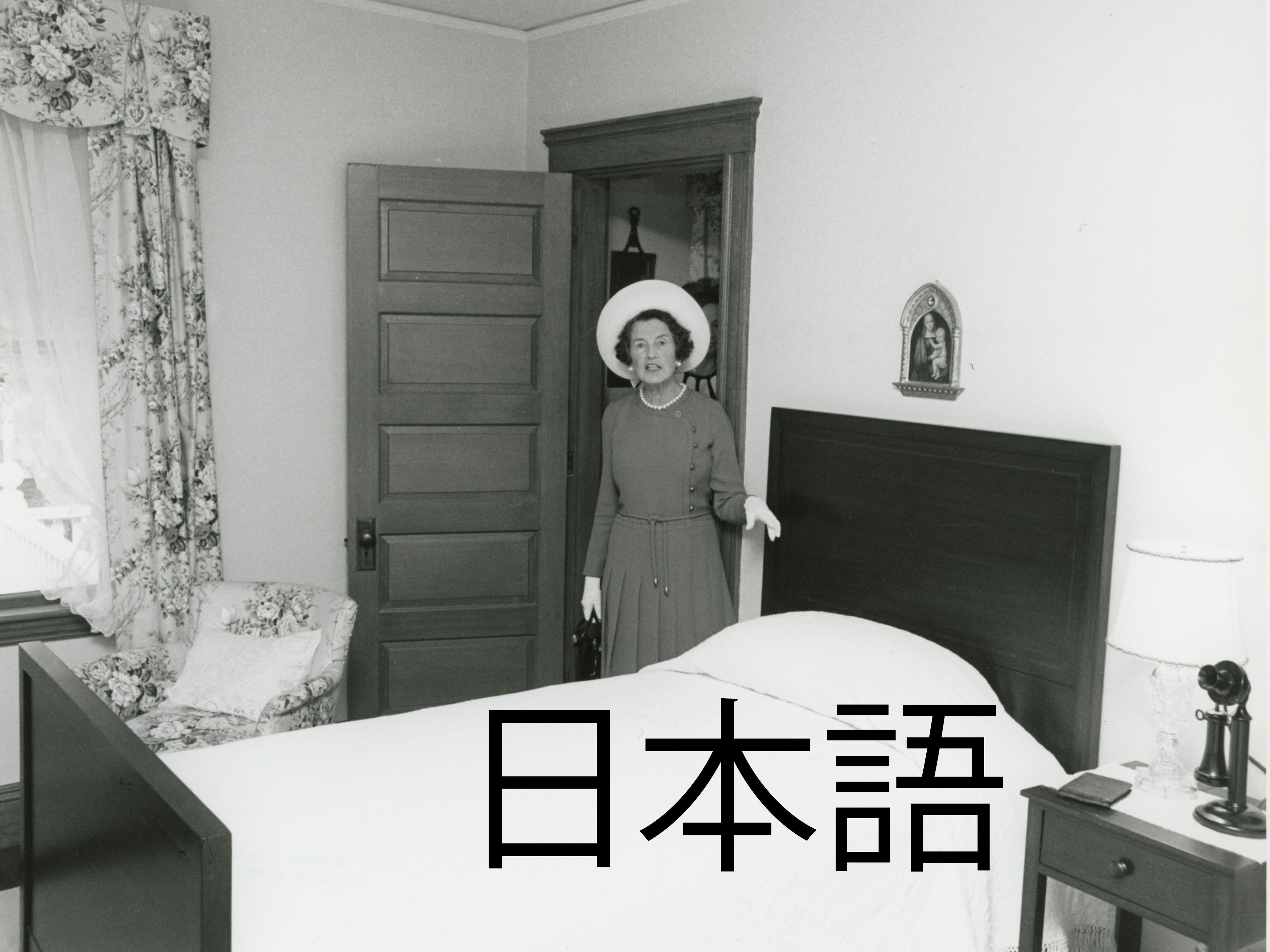 Woman in white hat standing next to twin bed