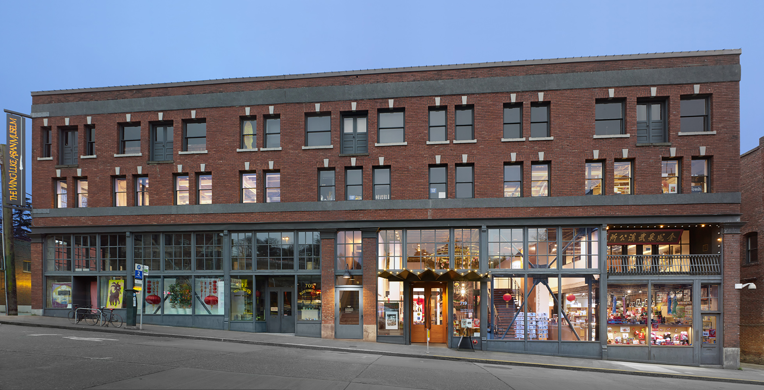 Three-story structure with a red brick fa&ccedil;ade, punctuated by numerous windows.