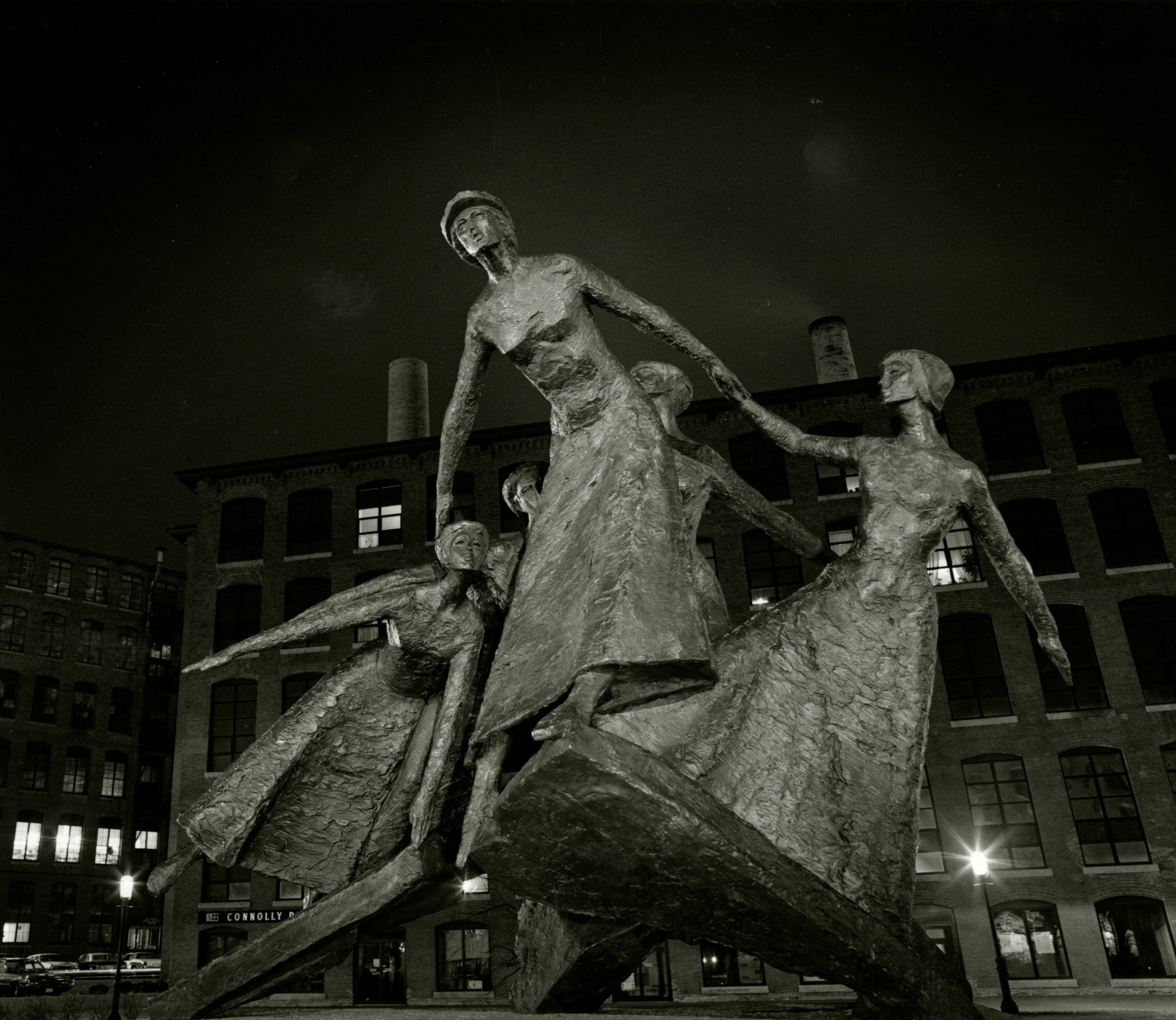 A metal sculpture of five women, together in a group looking into the distance.
