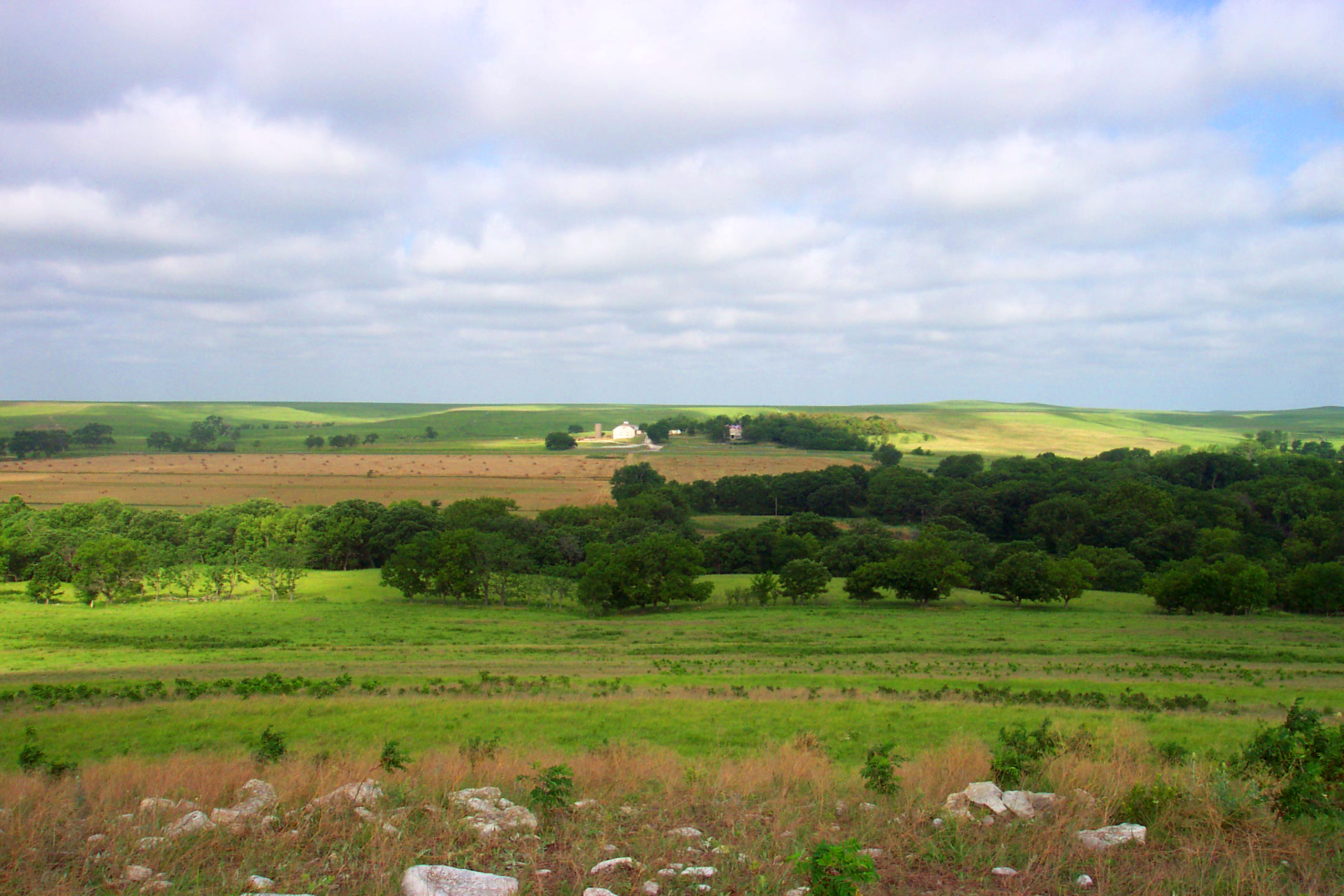 Image of ranch at center of picture with blue sky and clouds