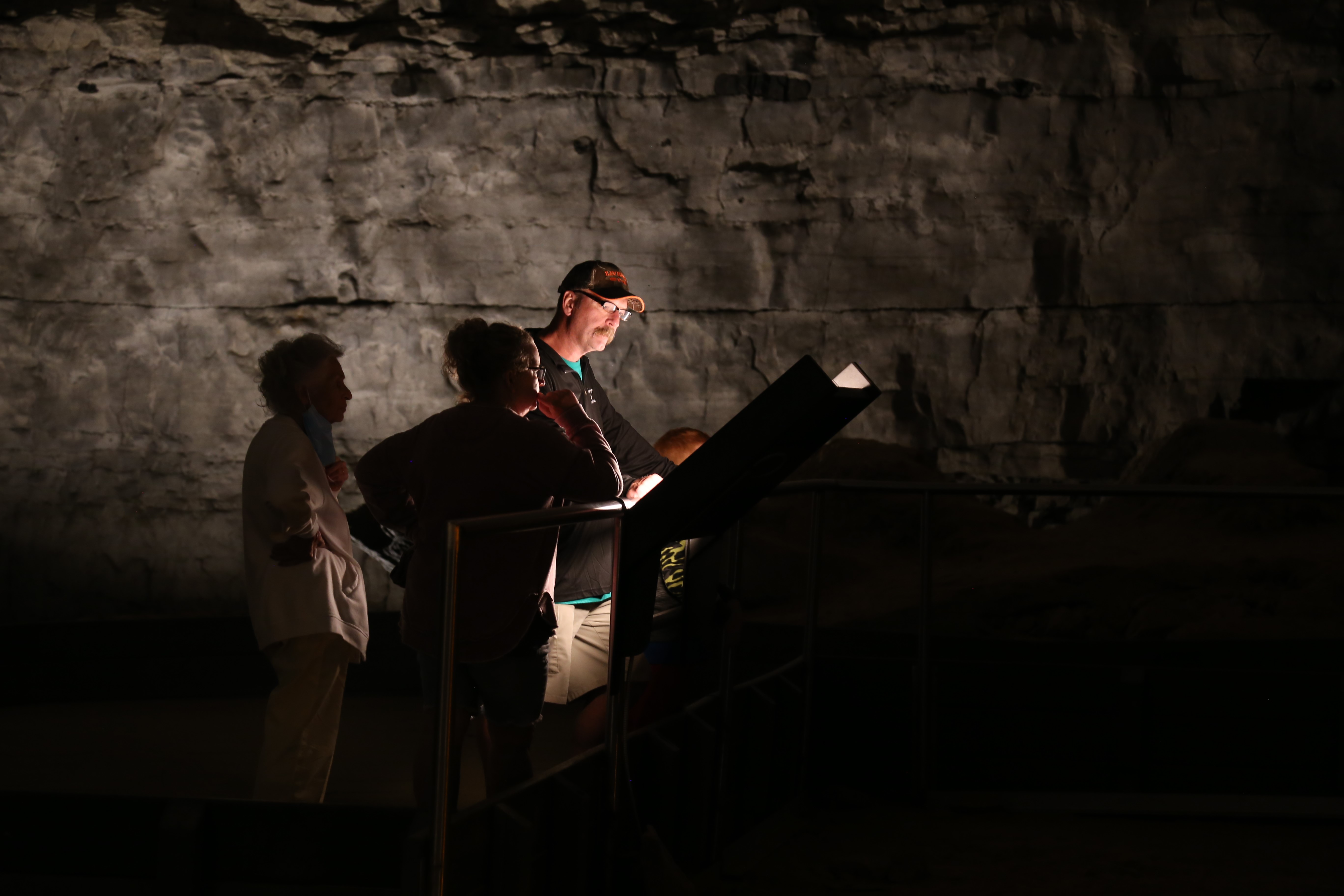 A group of three people read a sign inside of a cave.