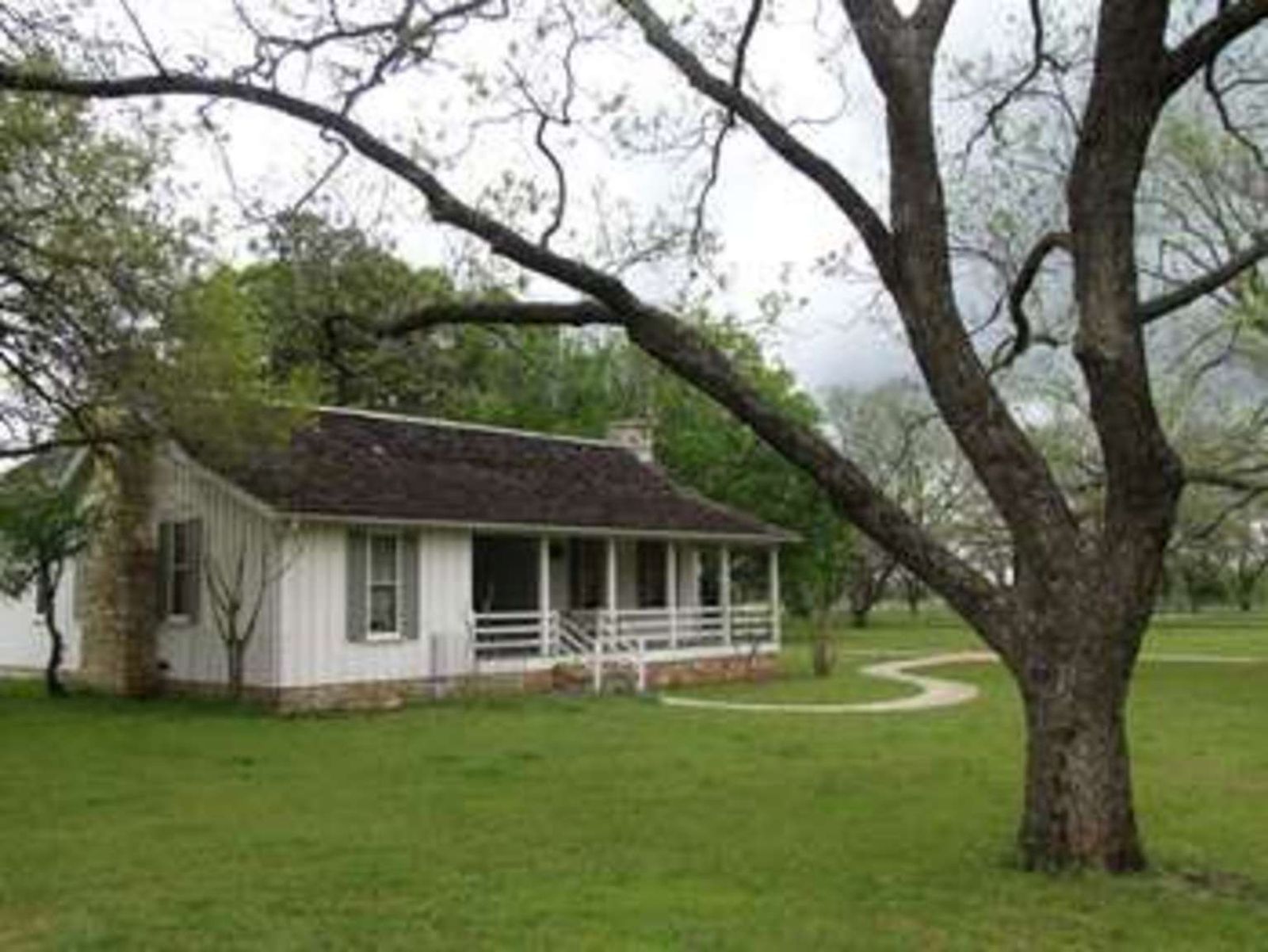 A small white house surrounded by trees.