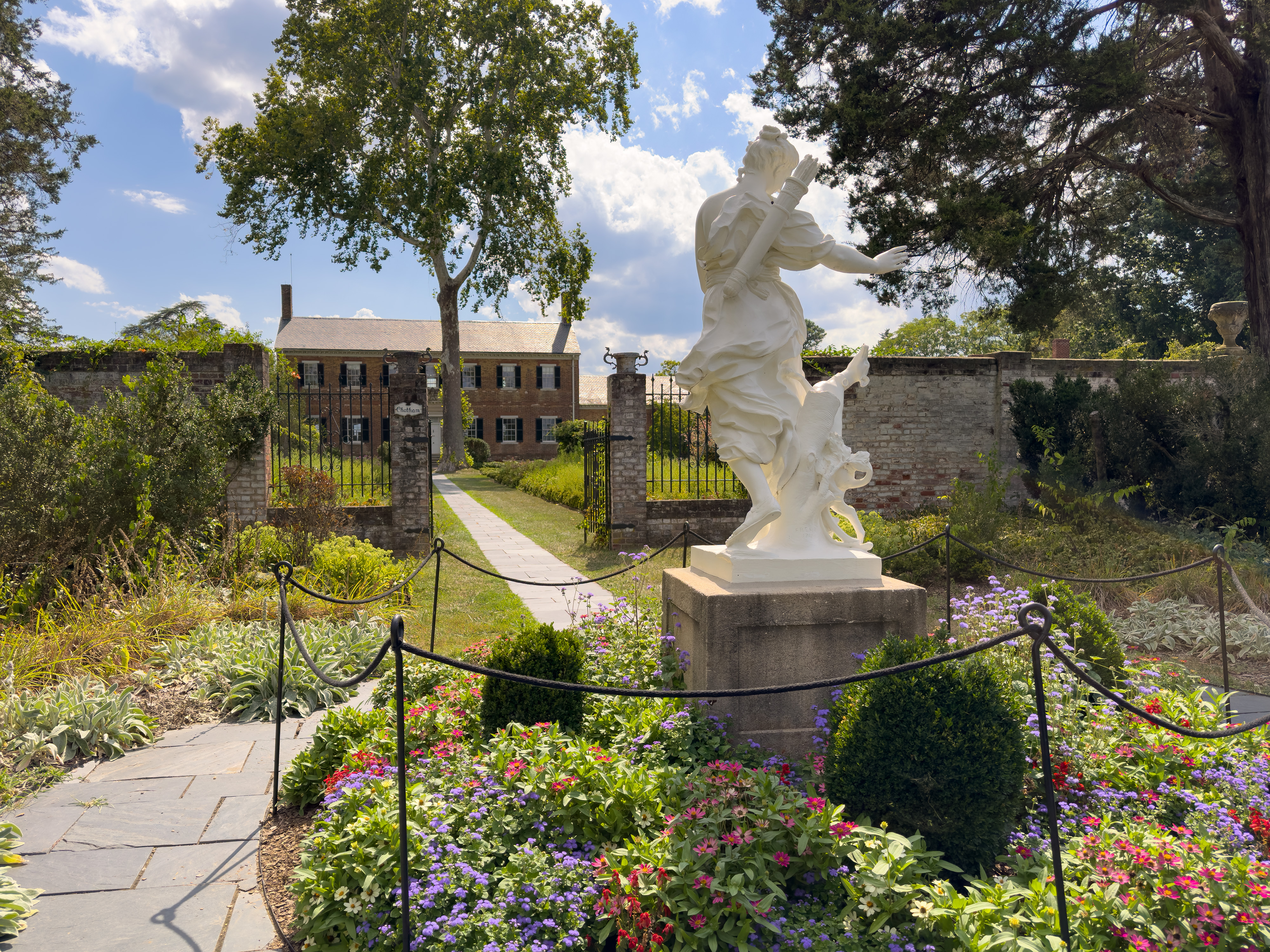 A statue of Roman Diana in a garden entrance to a historic garden and house,
