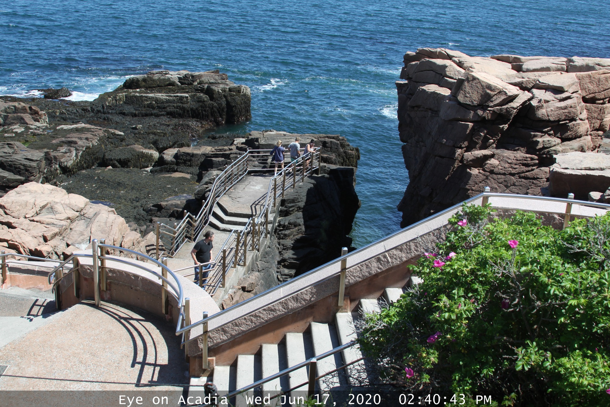 Staircase descending towards granite cliffs and ocean water.