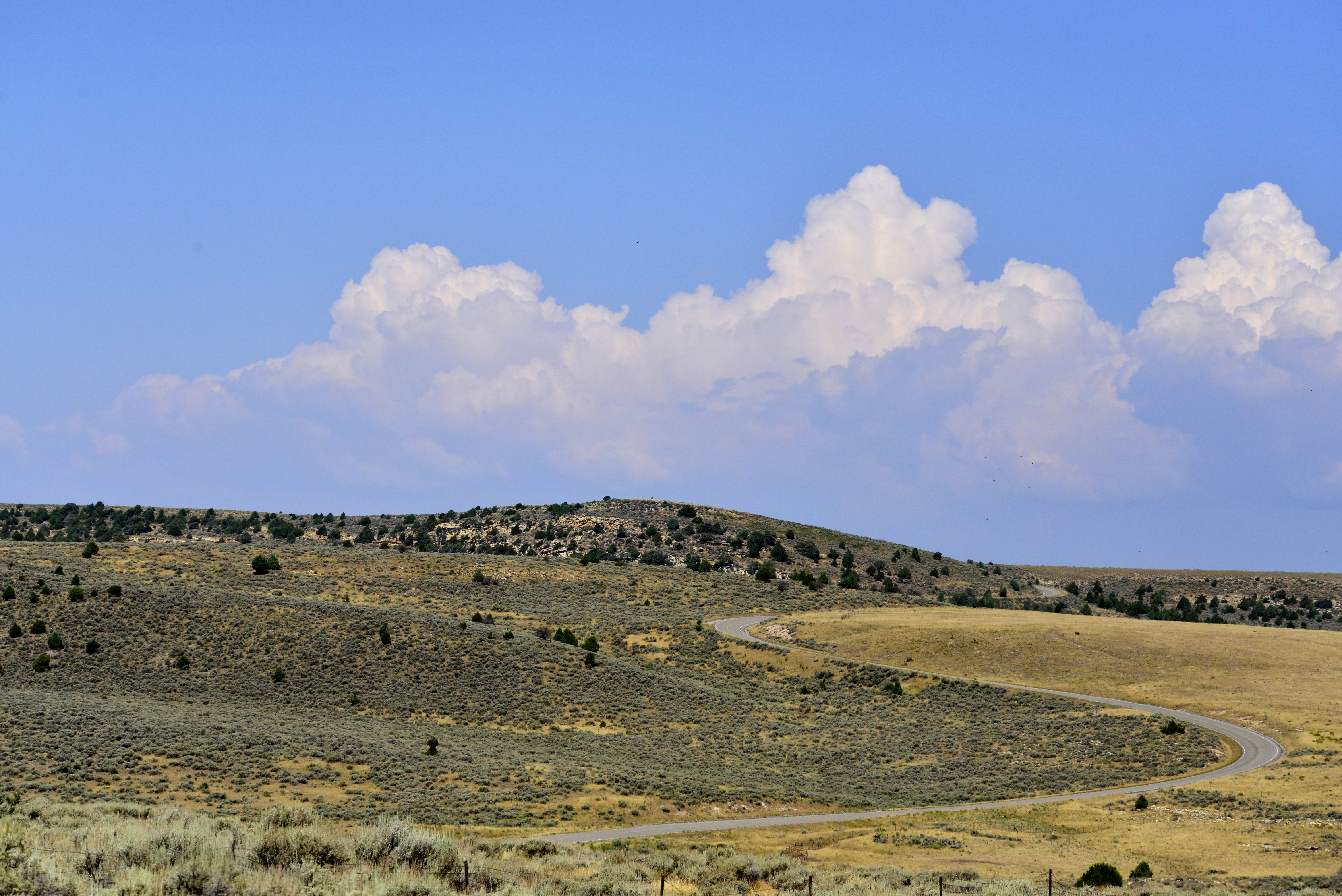 A paced two-lane road winding through a rugged plateau area.