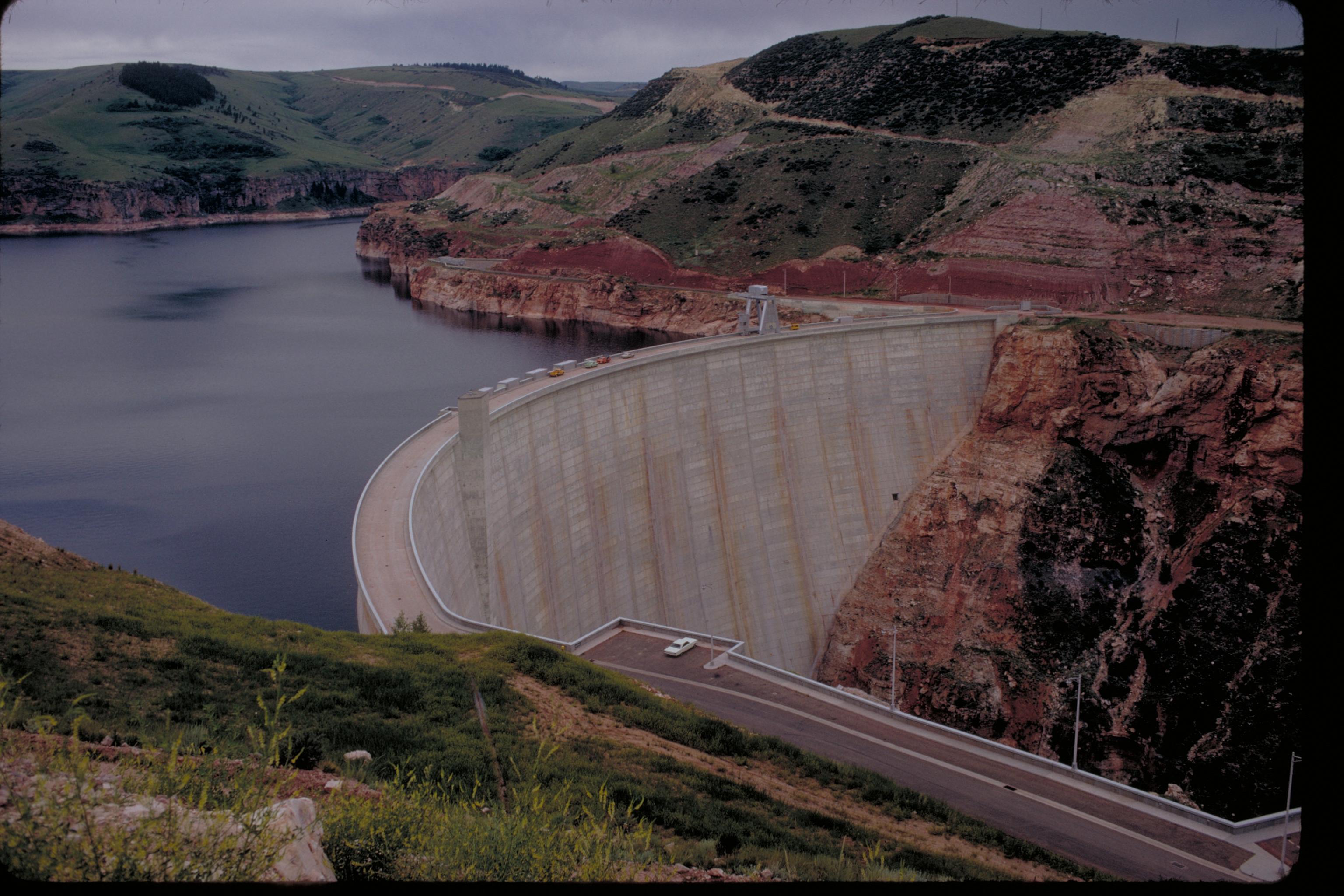 A large dam extends between two hills with water on one side.