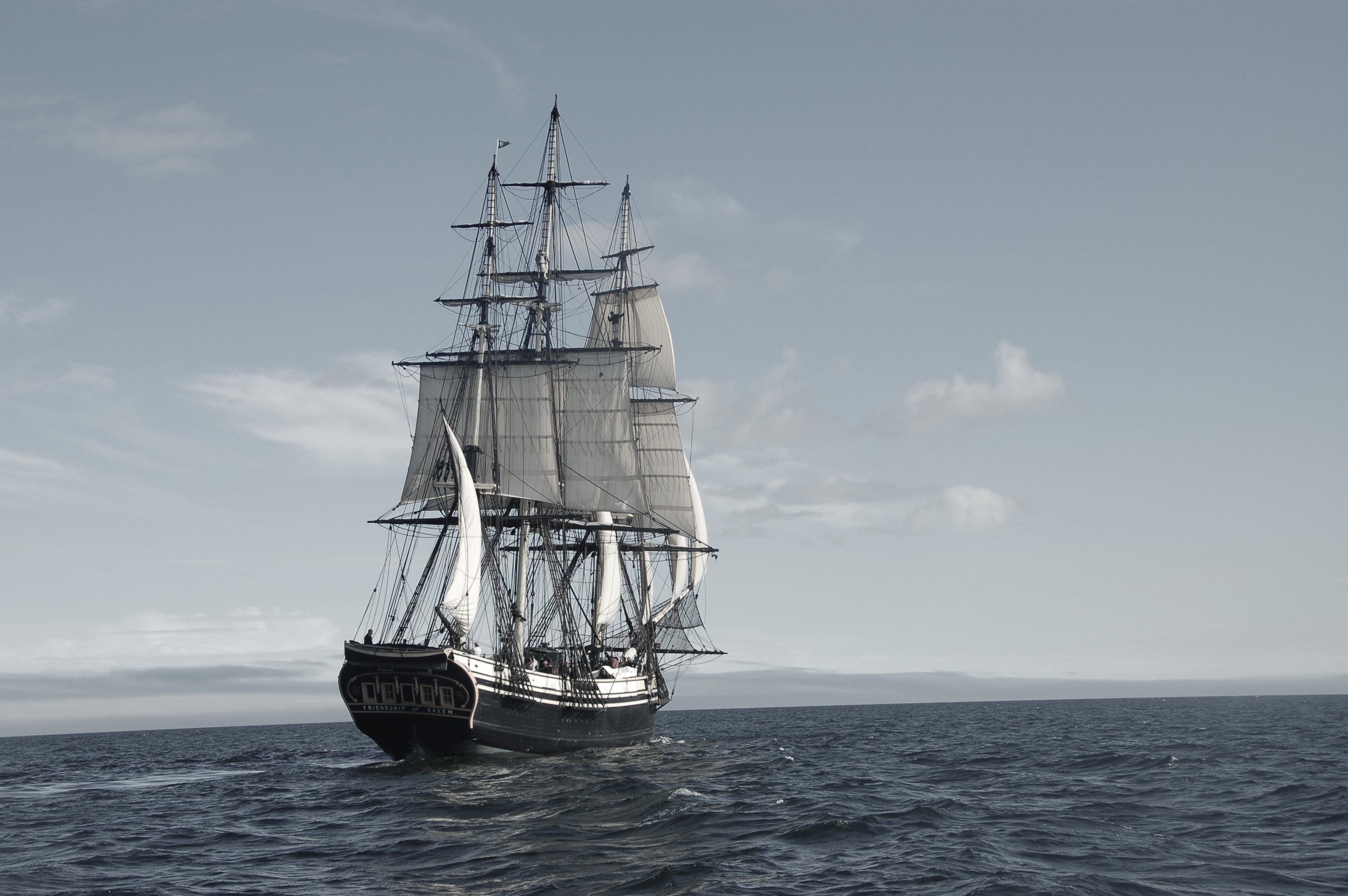 Black and white photo of large sailing vessel travelling through open water.