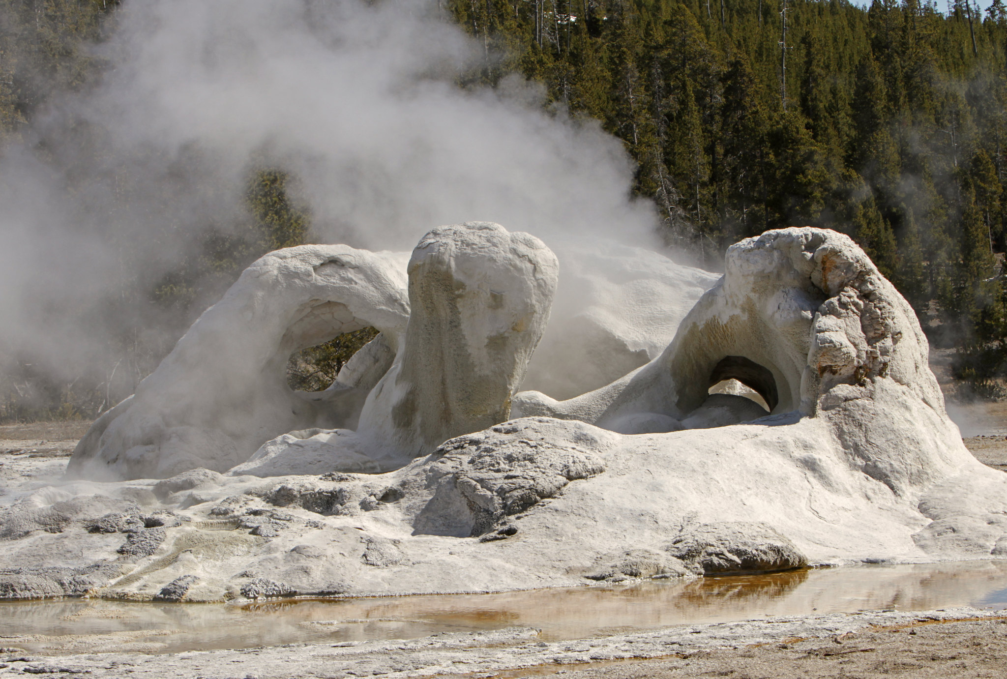 Steam rises up from a odd-shaped mound of white and grey rock.