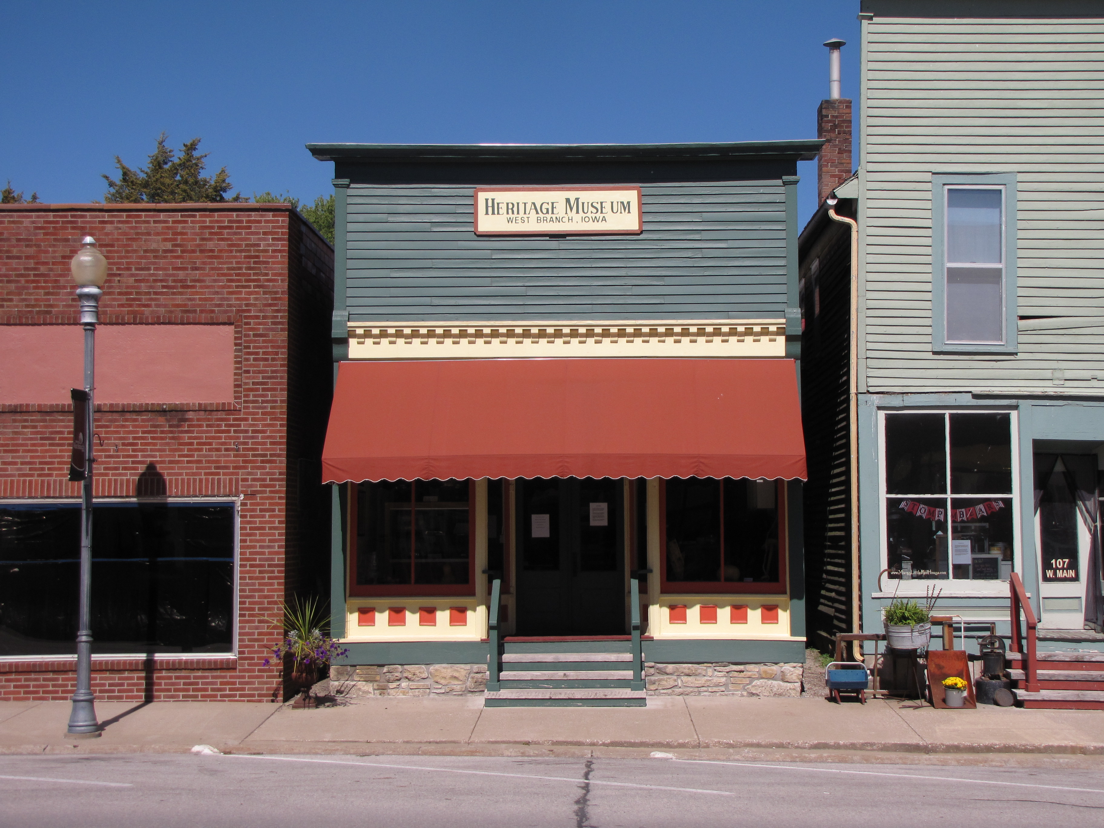 A restored wooden storefronts has cream trim and a red orange awning.